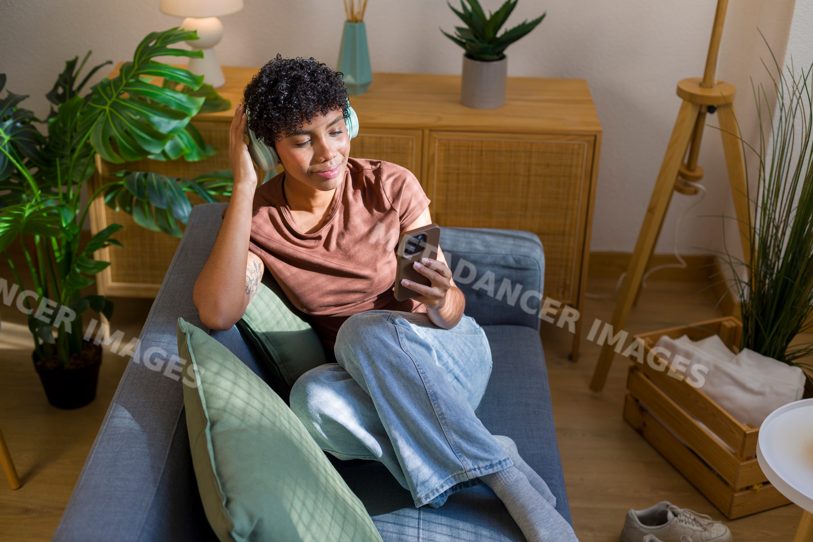 Young African American woman relaxing on sofa listening to music