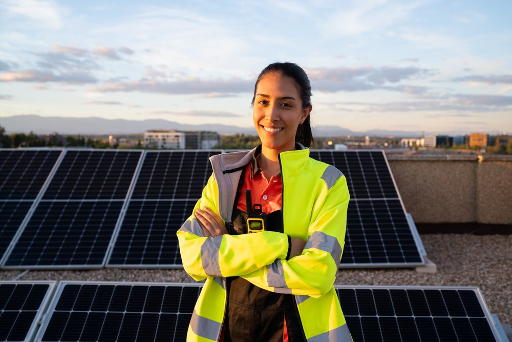 Hispanic woman engineer standing by solar panels on rooftop