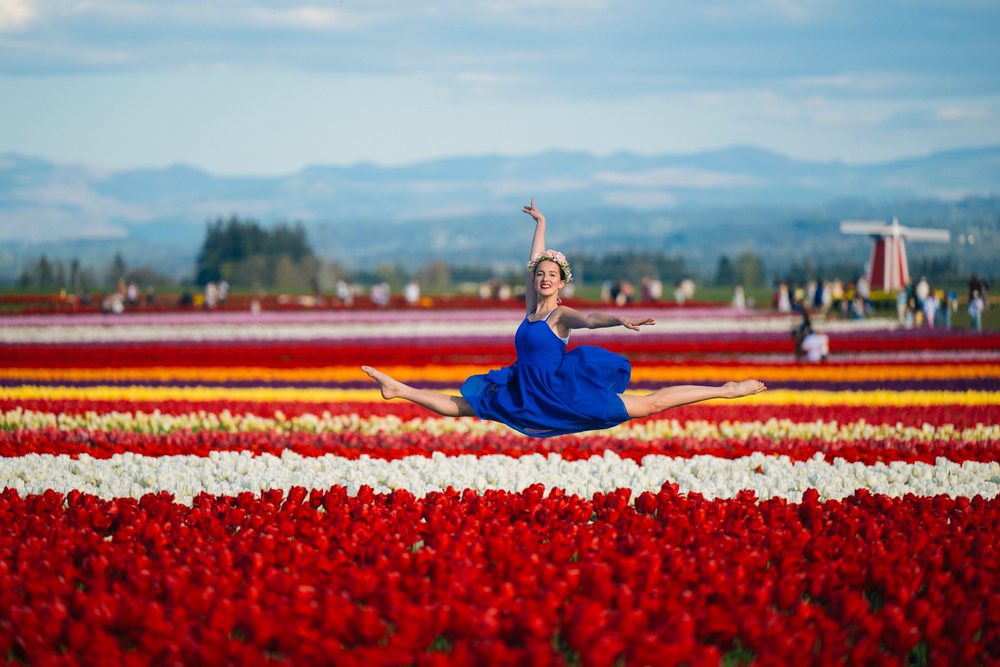 Ballet white dancer leaping over colorful tulip fields