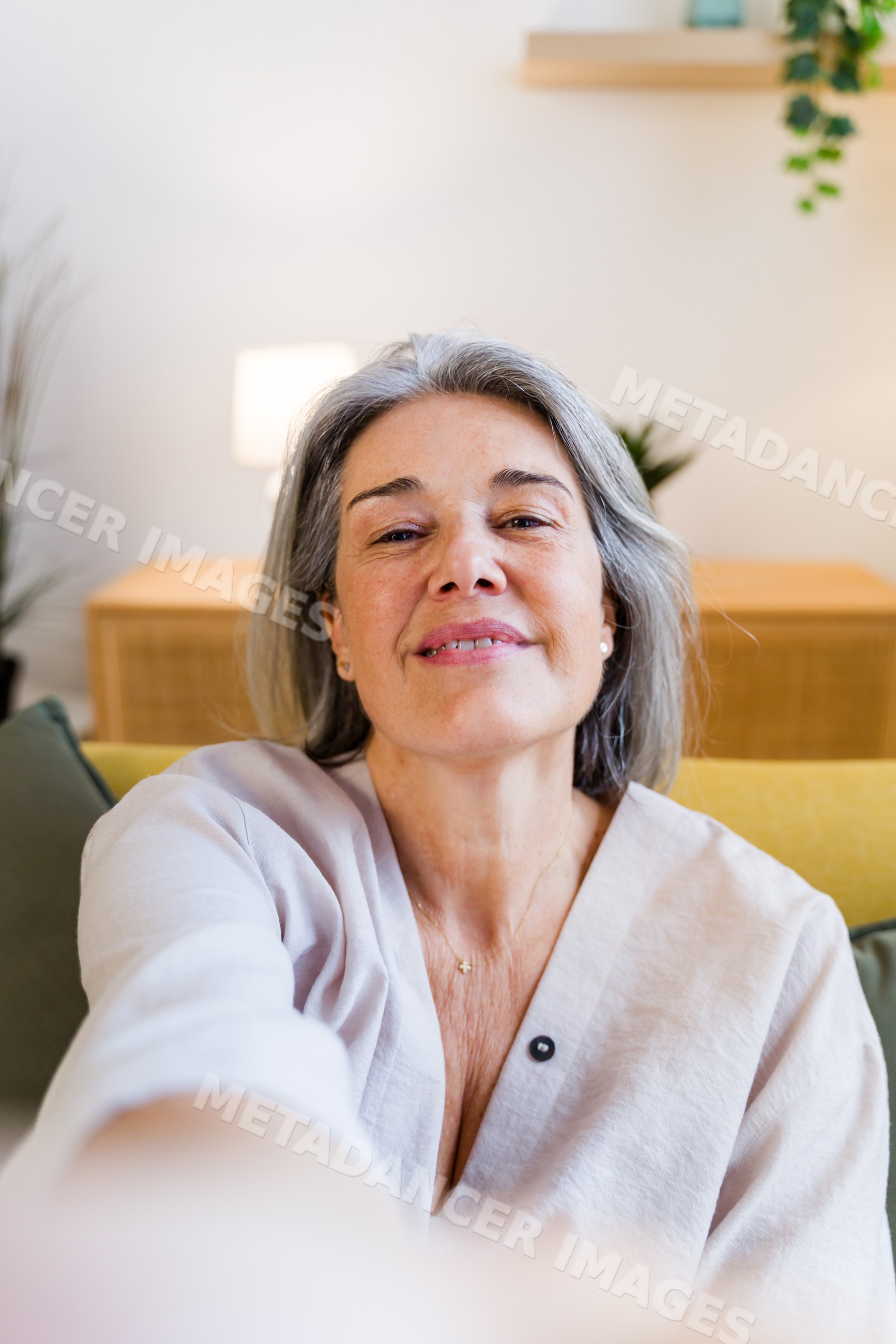 Middle-aged white woman taking selfie on sofa in living room