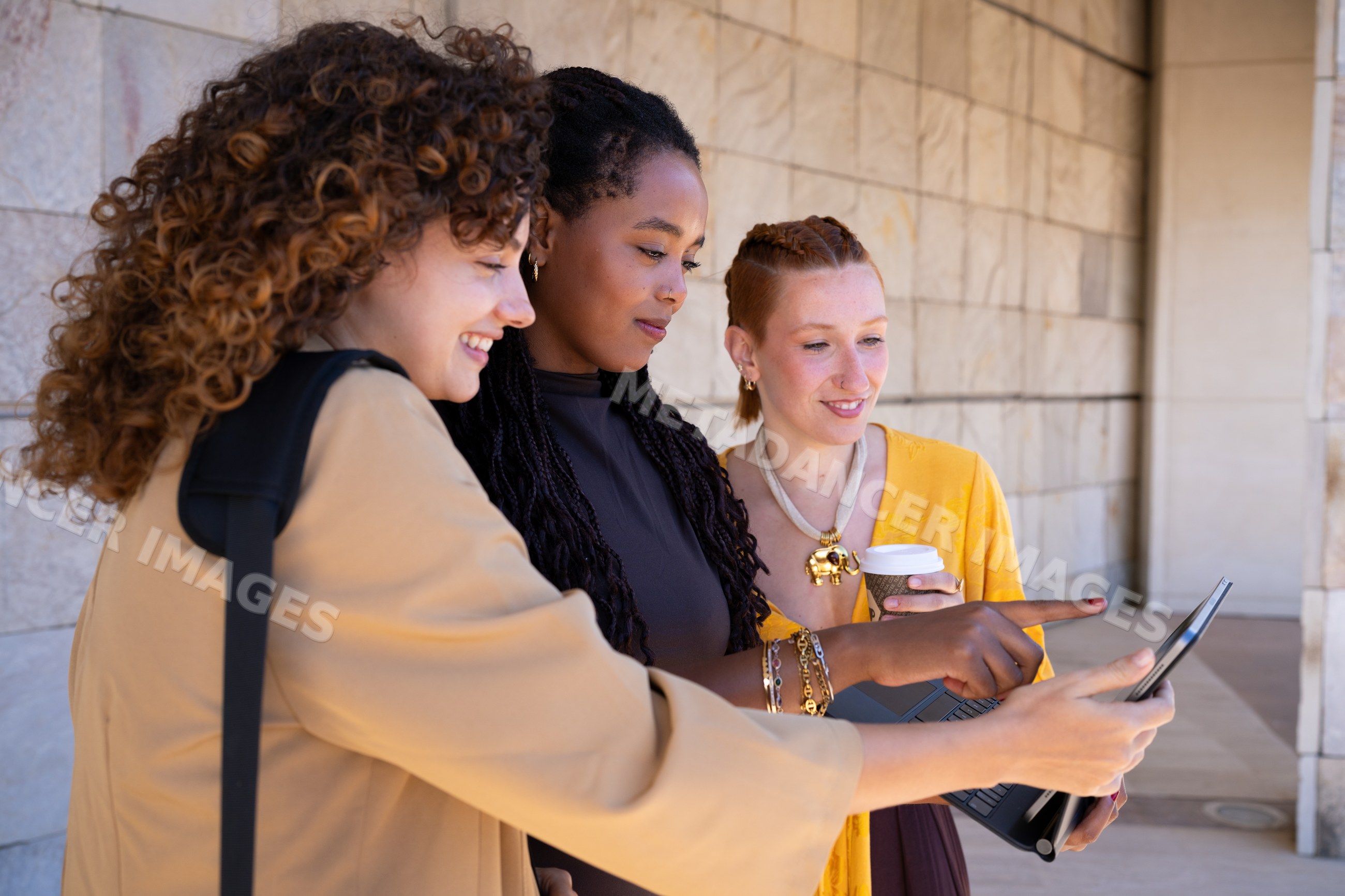 Three African American and white women collaborating using a laptop