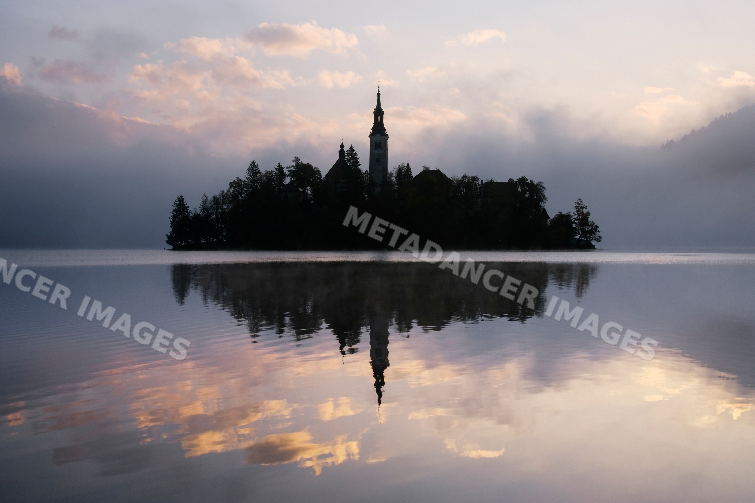 Church of assumption silhouetted on lake bled island at sunrise
