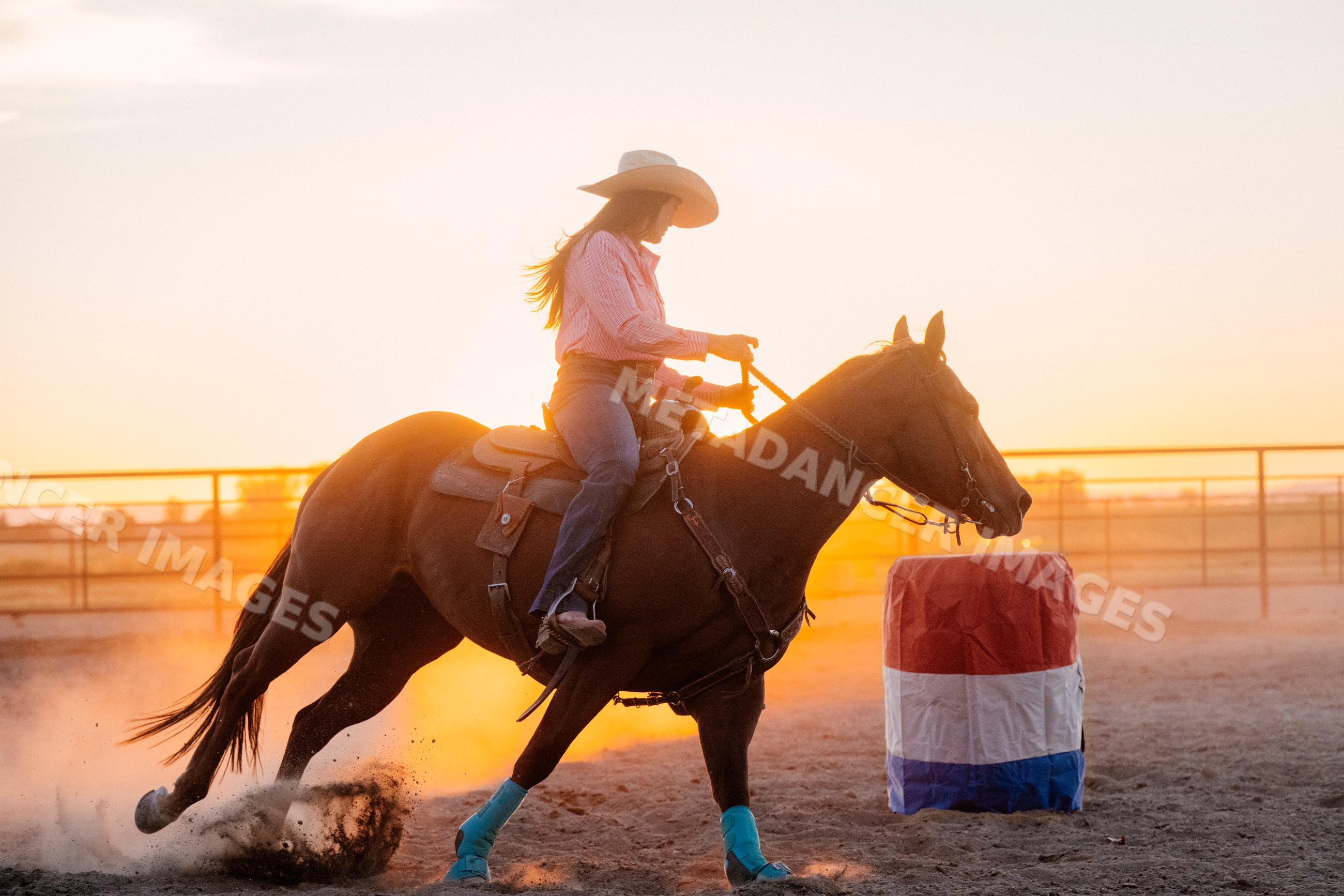 White woman riding horse at sunset during barrel racing