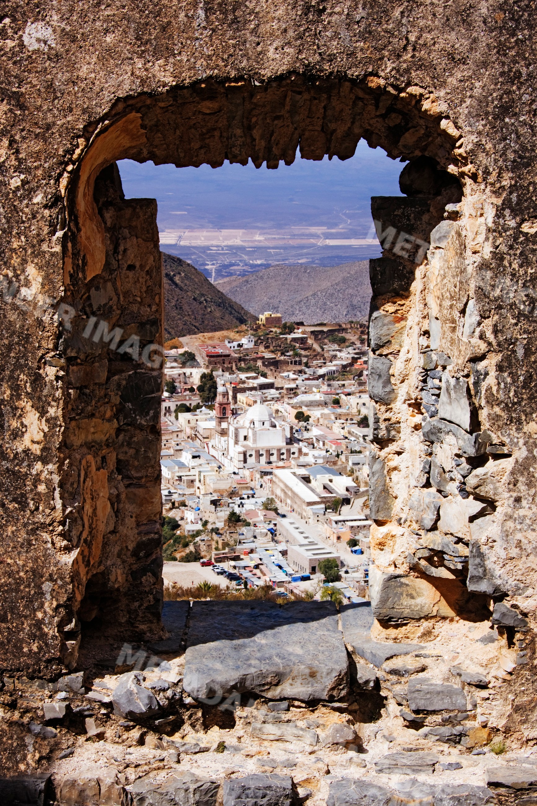 View of real de catorce village through stone ruins archway
