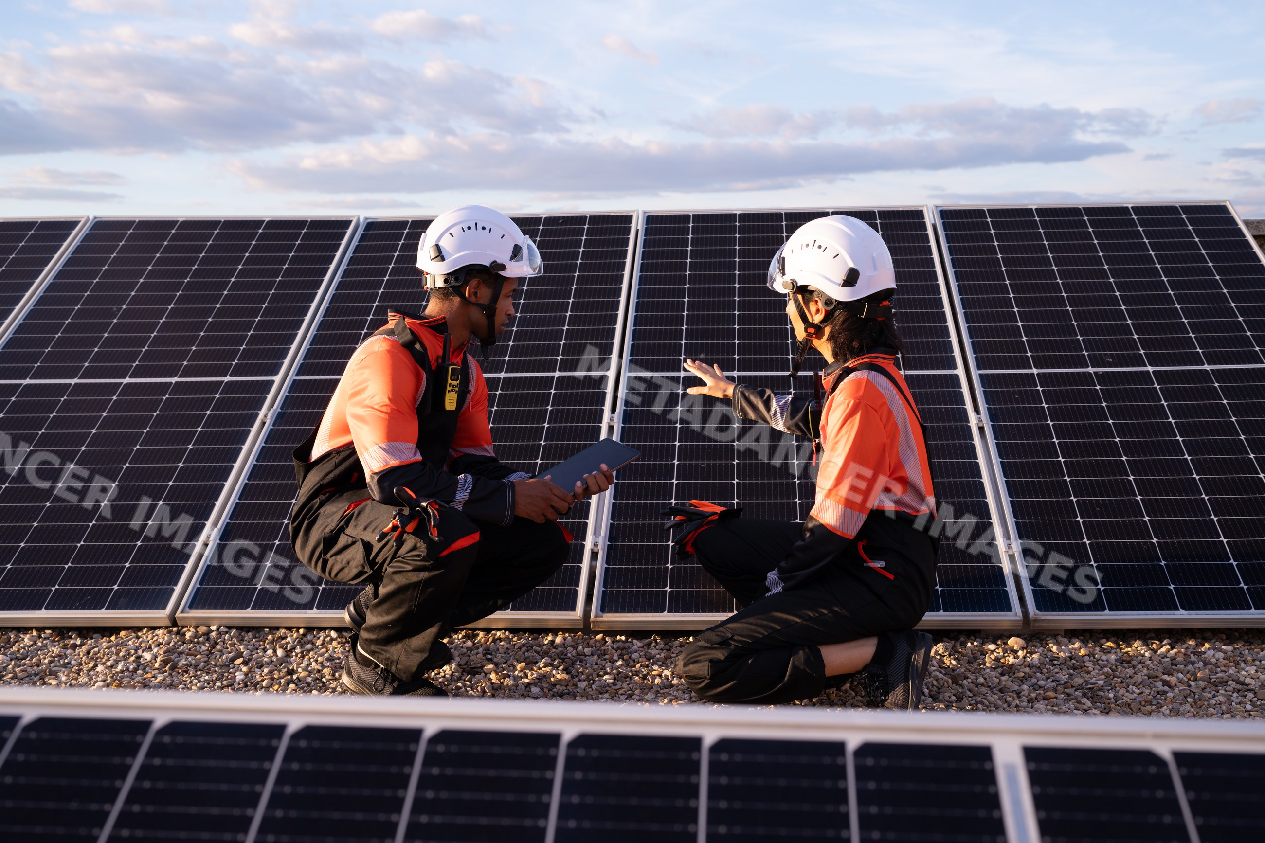 Hispanic workers inspecting solar panels on solar energy installation