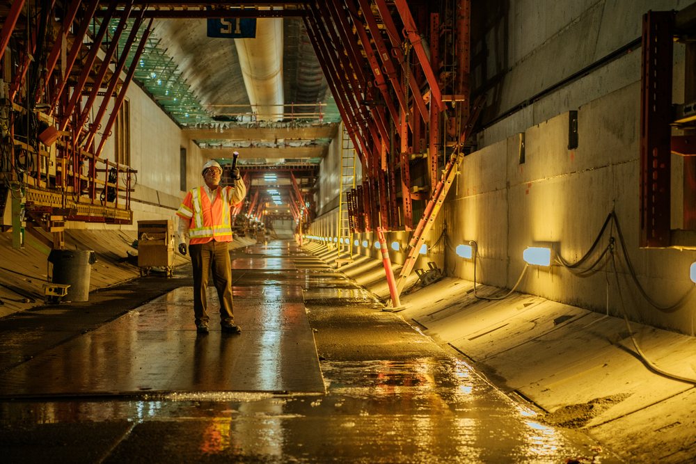 White construction worker inspects underground tunnel for safety