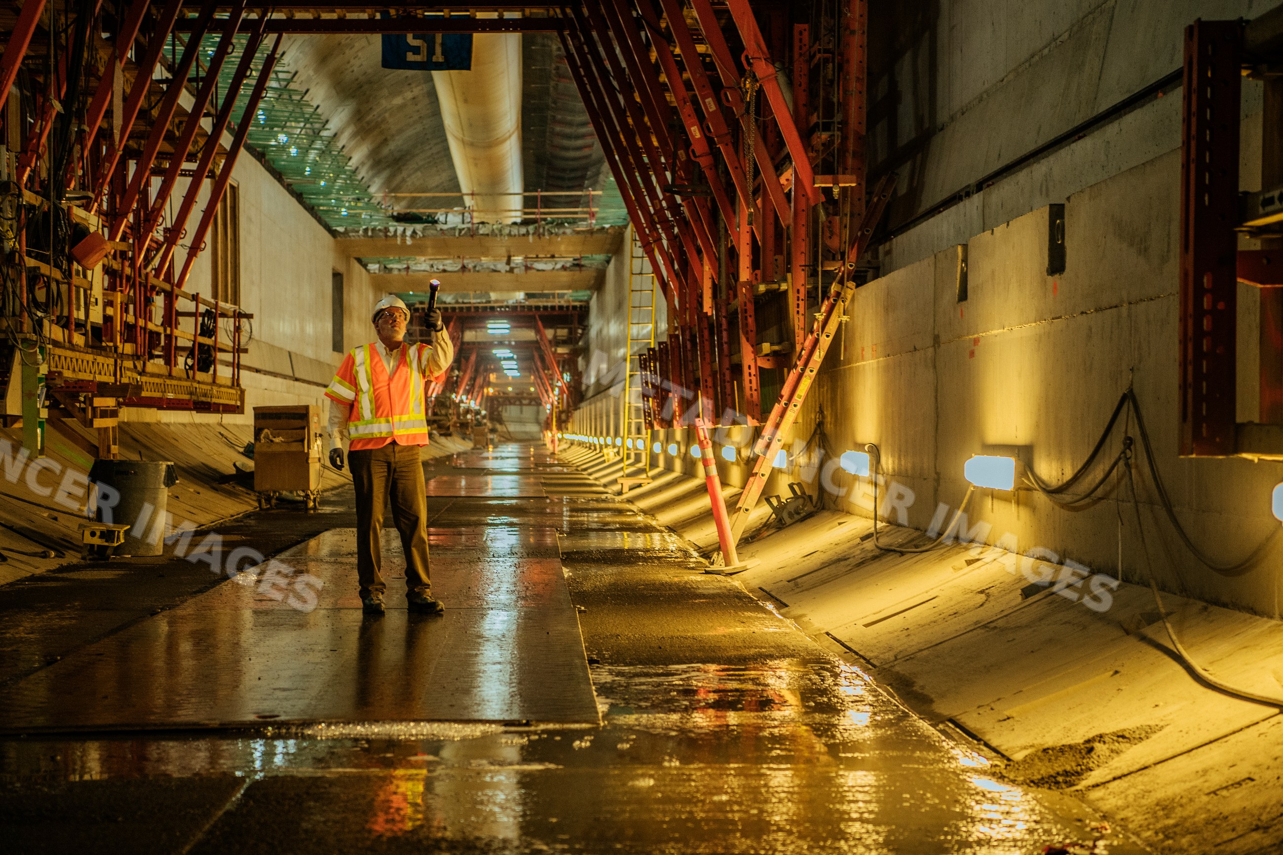 A construction white worker inspects an underground tunnel
