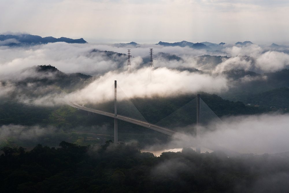 Centennial bridge crossing panama canal amid fog and tropical forest