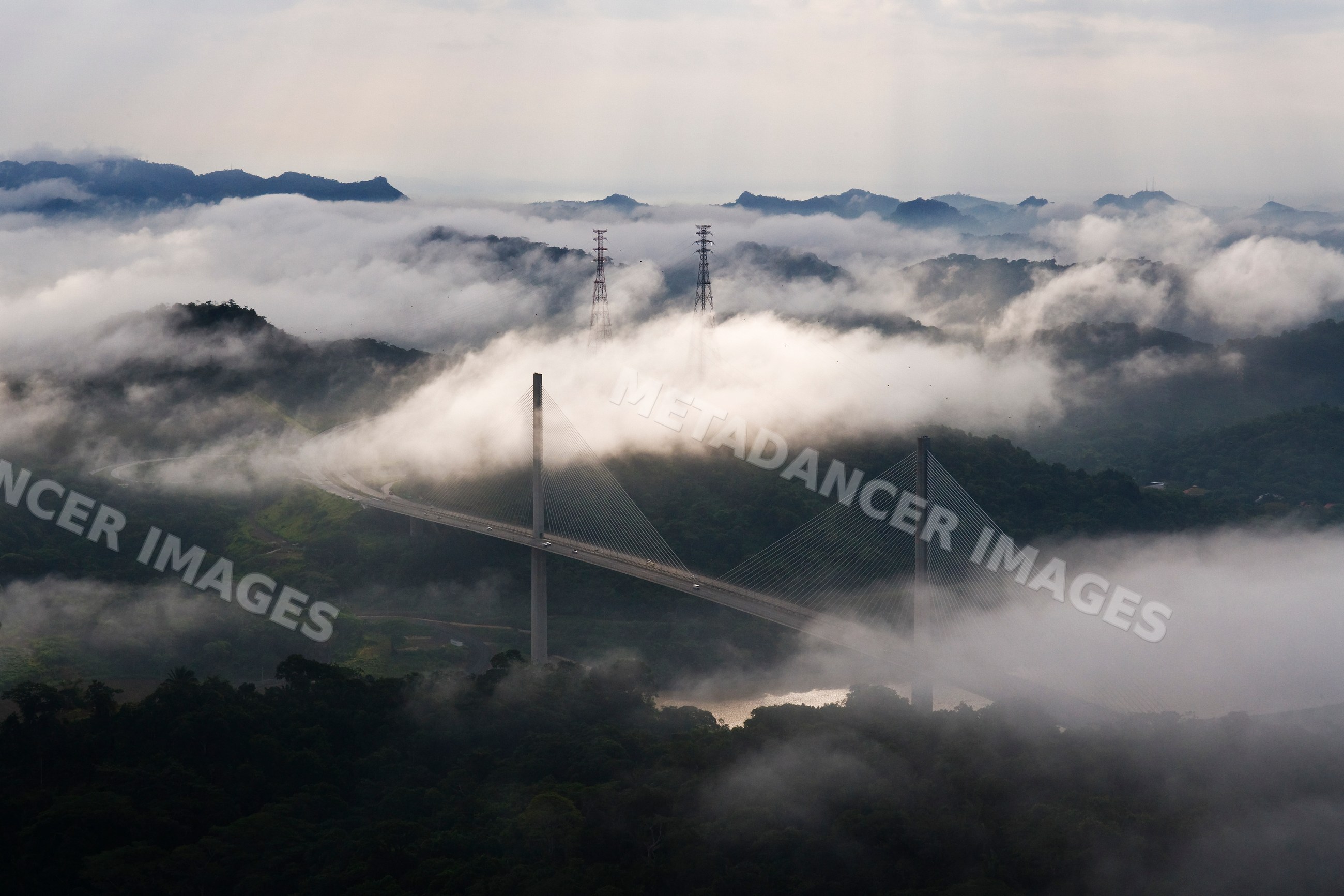 Centennial bridge crossing panama canal amid fog and tropical forest