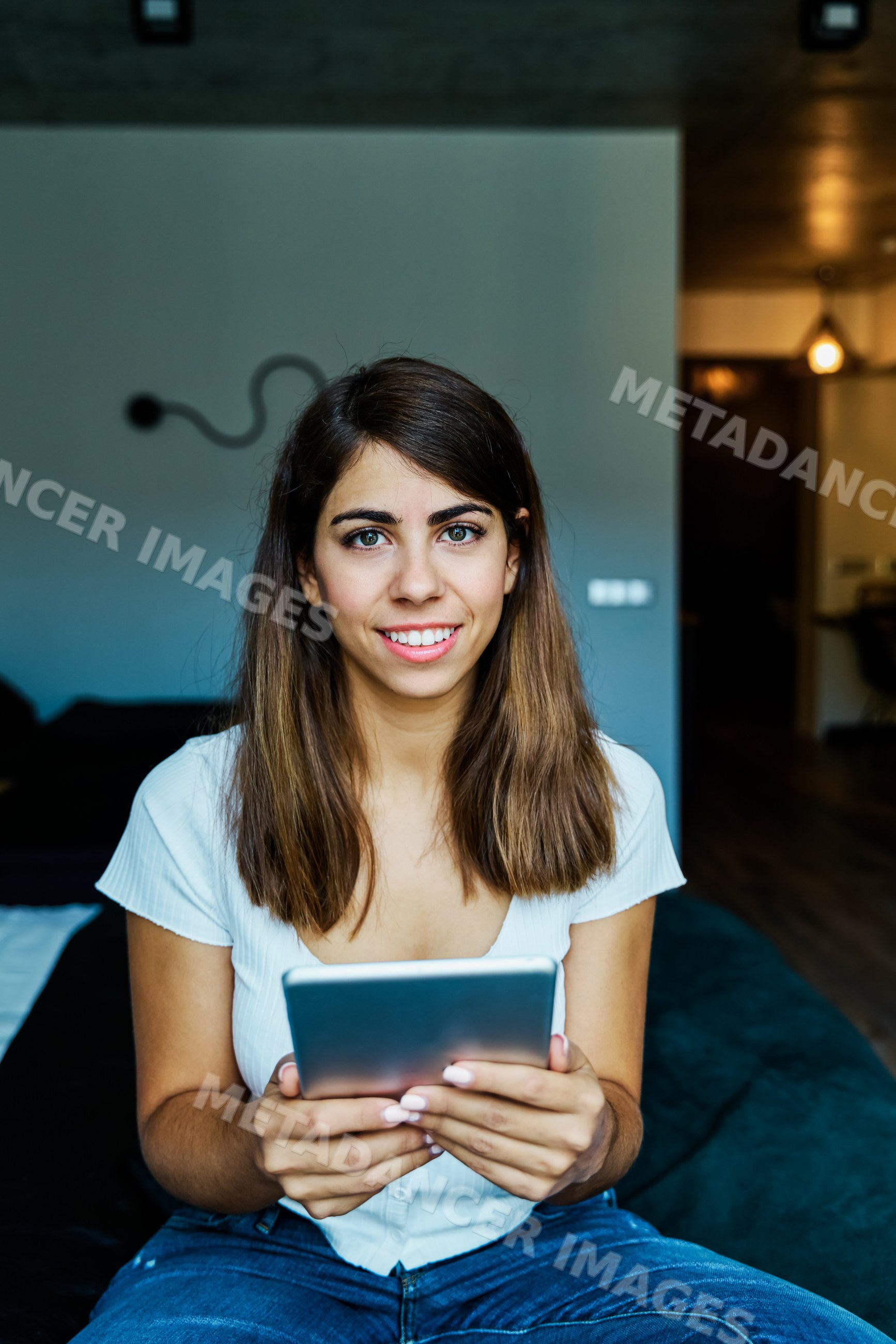 A young woman holding a tablet and smiling indoors in a hotel