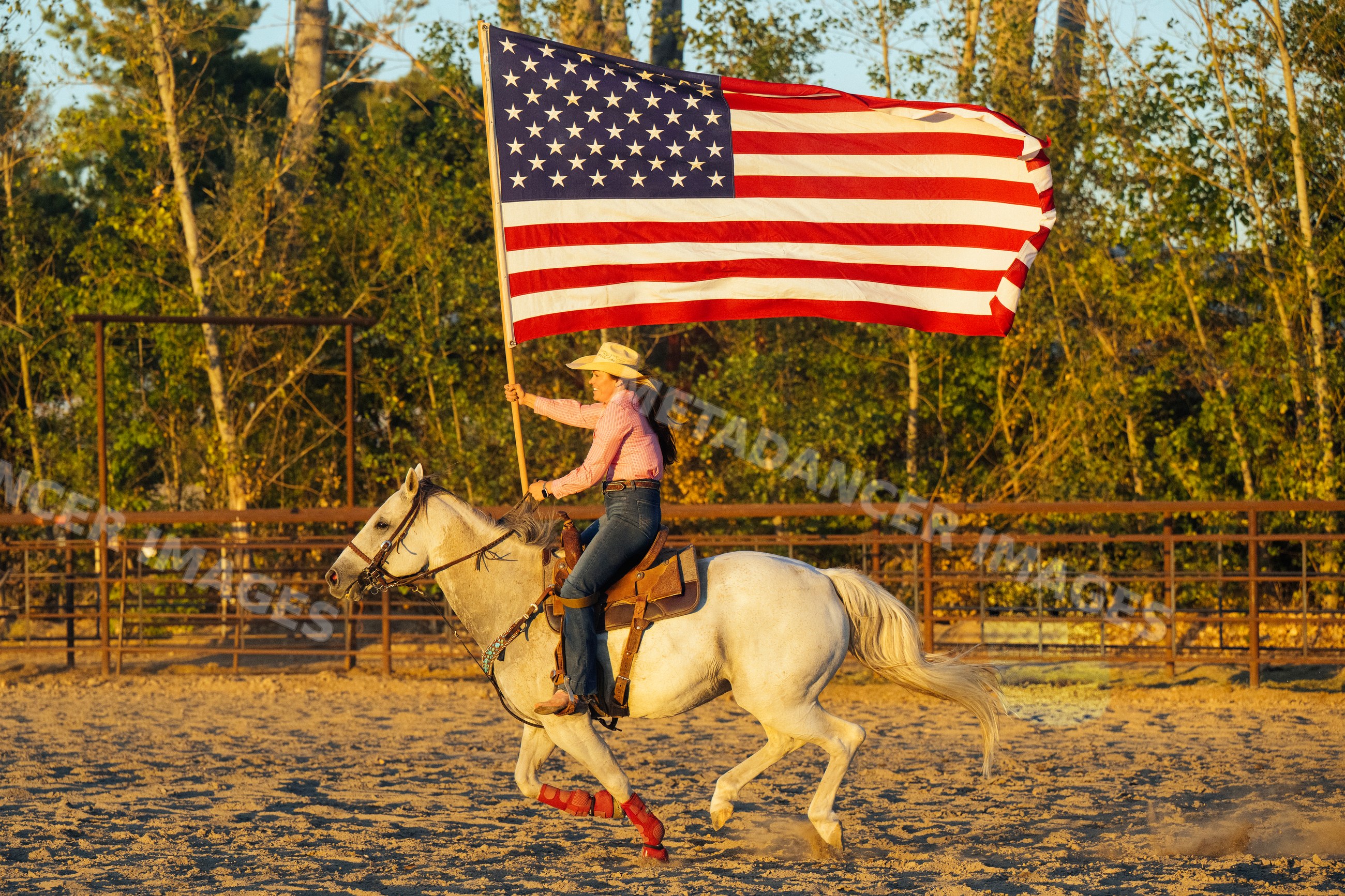 White woman riding horse carrying american flag