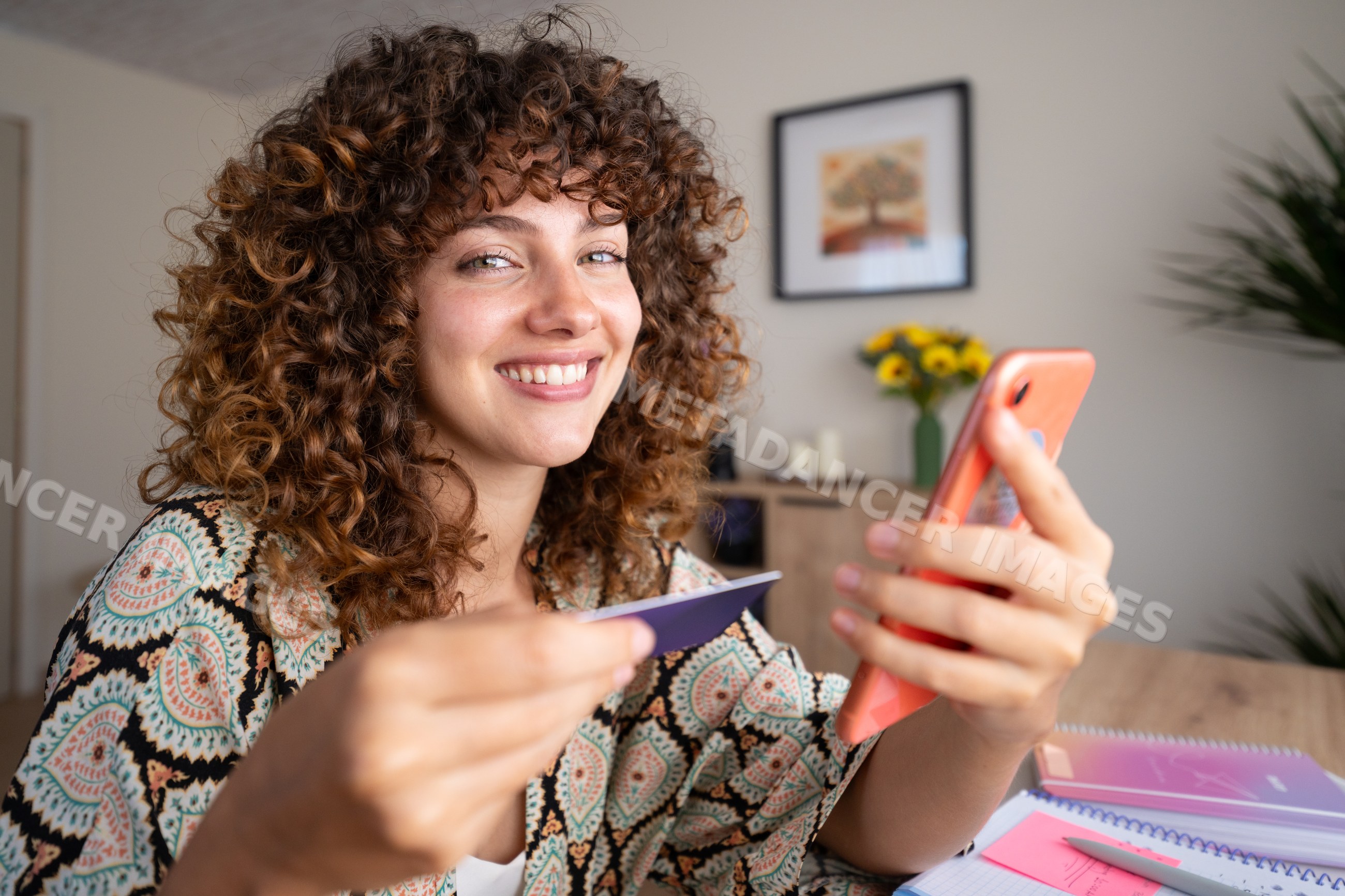 White girl smiling holding phone and card inside home in Spain