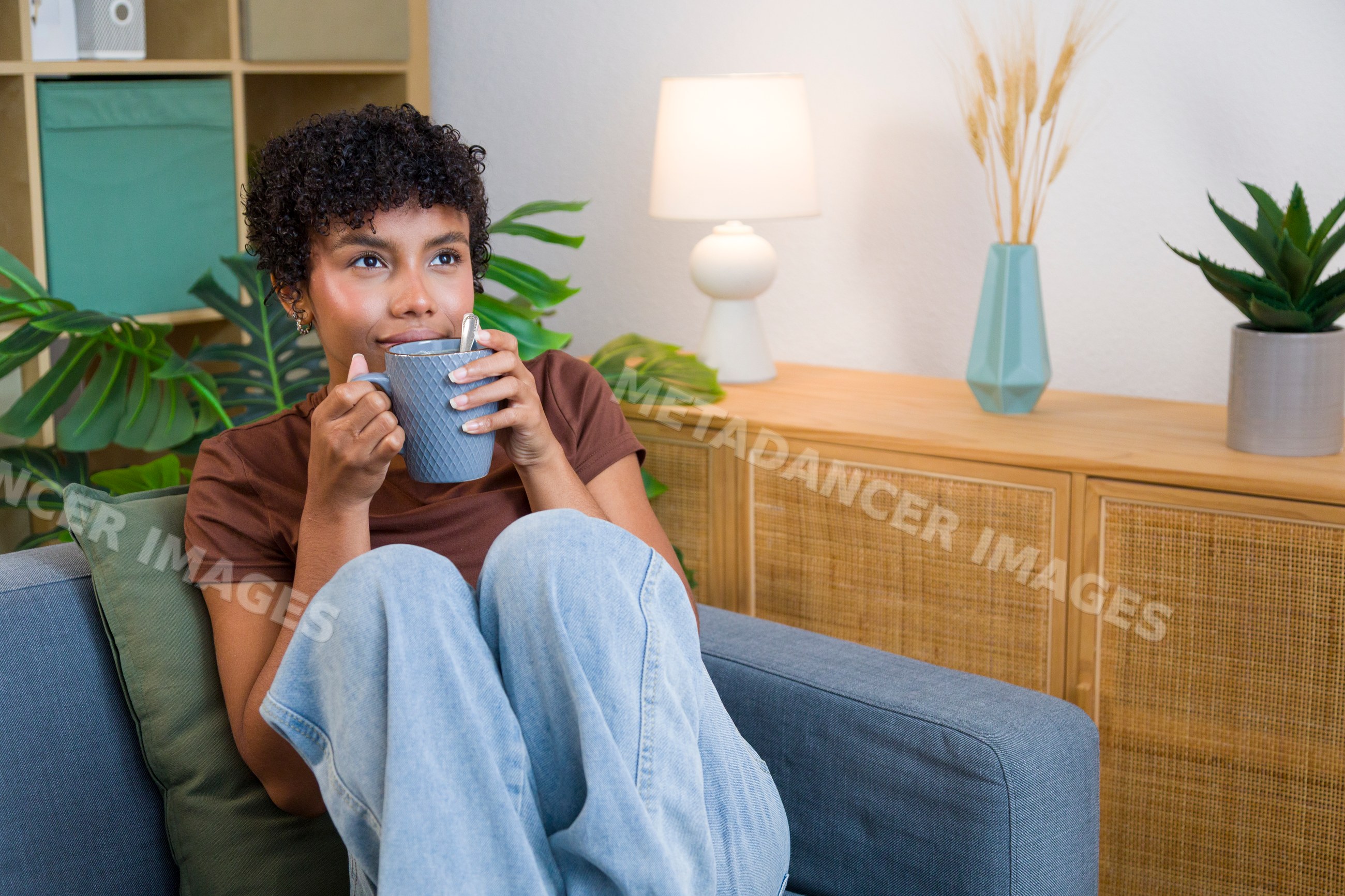 African American woman drinking hot beverage on a sofa