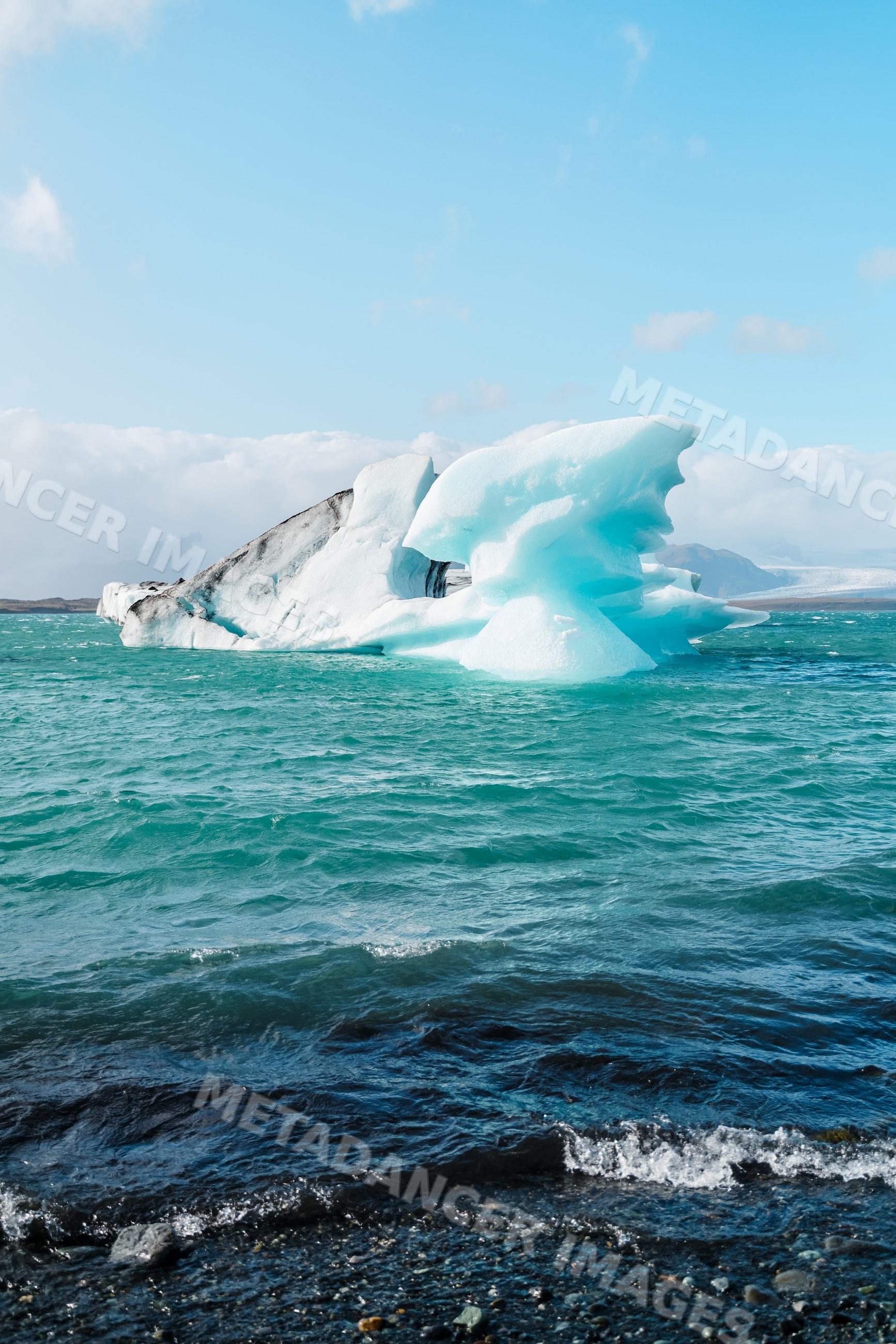 A large iceberg floats in icy water near a rocky shore