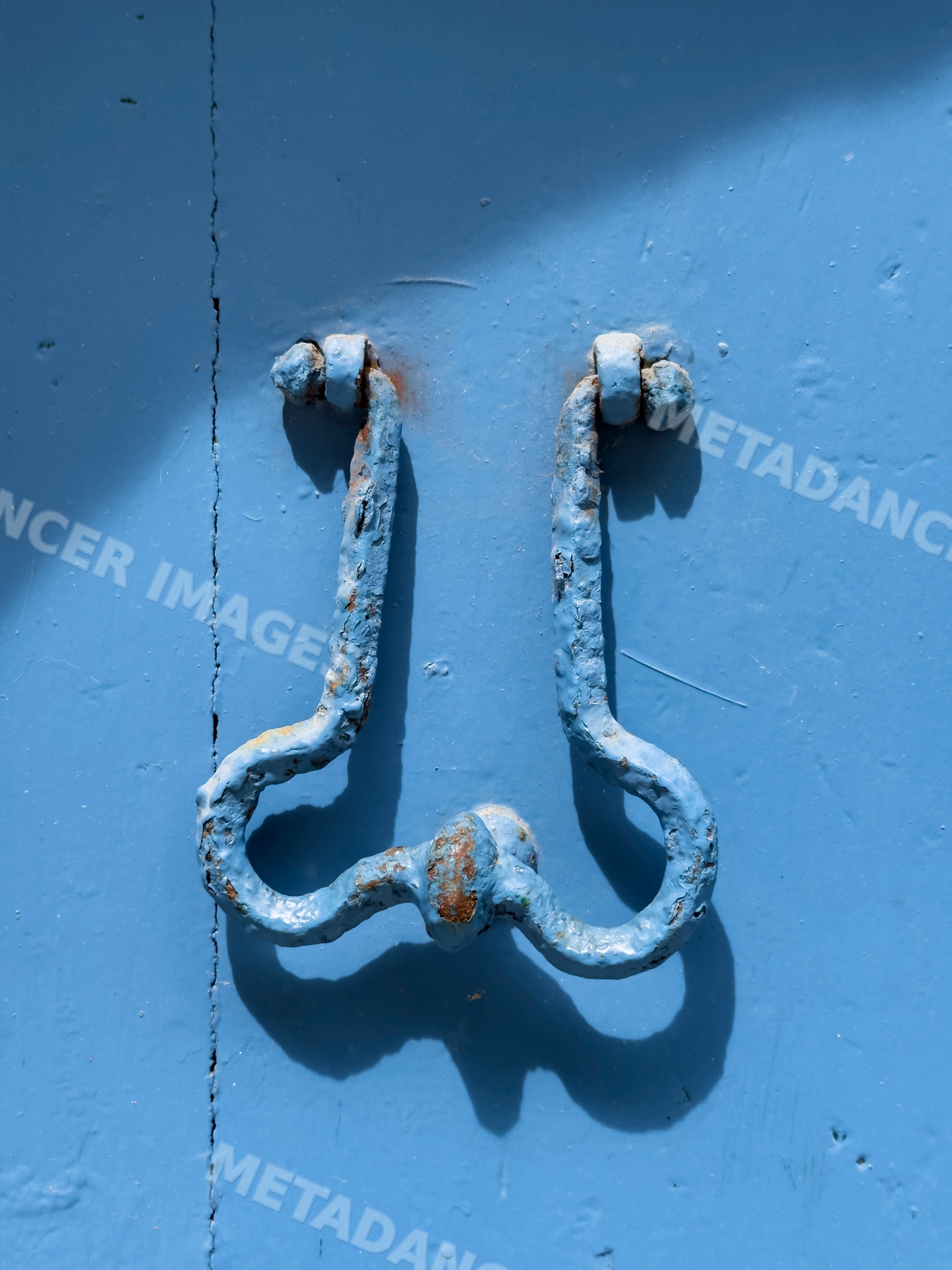 Weathered metal door knocker on blue door in chianalea, Italy