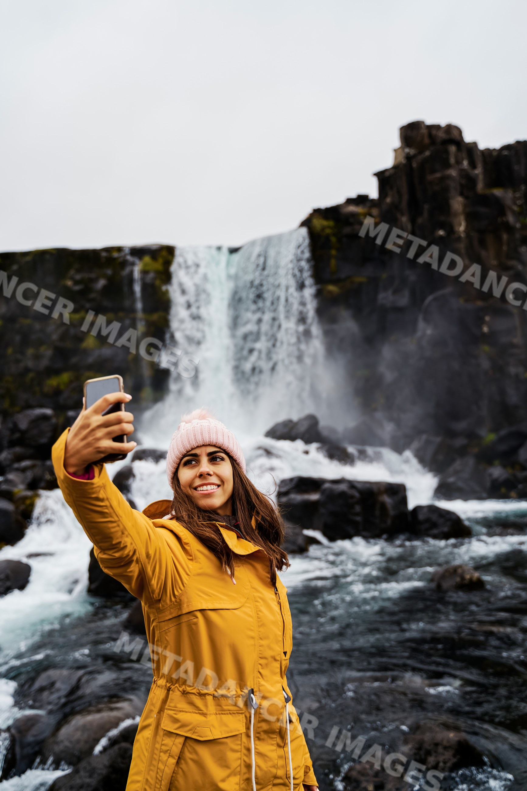 A white woman takes a selfie near a waterfall in Iceland