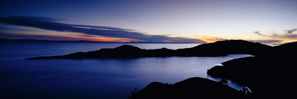 Lake titicaca sunset with silhouetted mountains and tranquil water