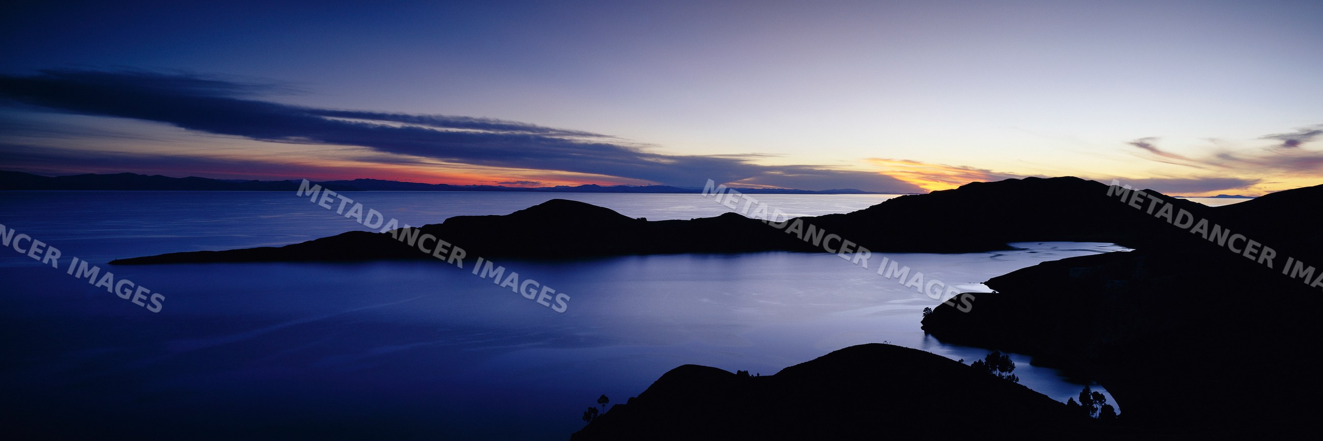 Lake titicaca sunset with silhouetted mountains and tranquil water