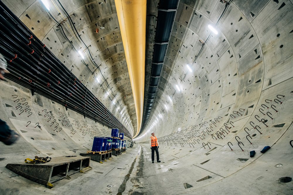 White construction worker inspects a large underground tunnel