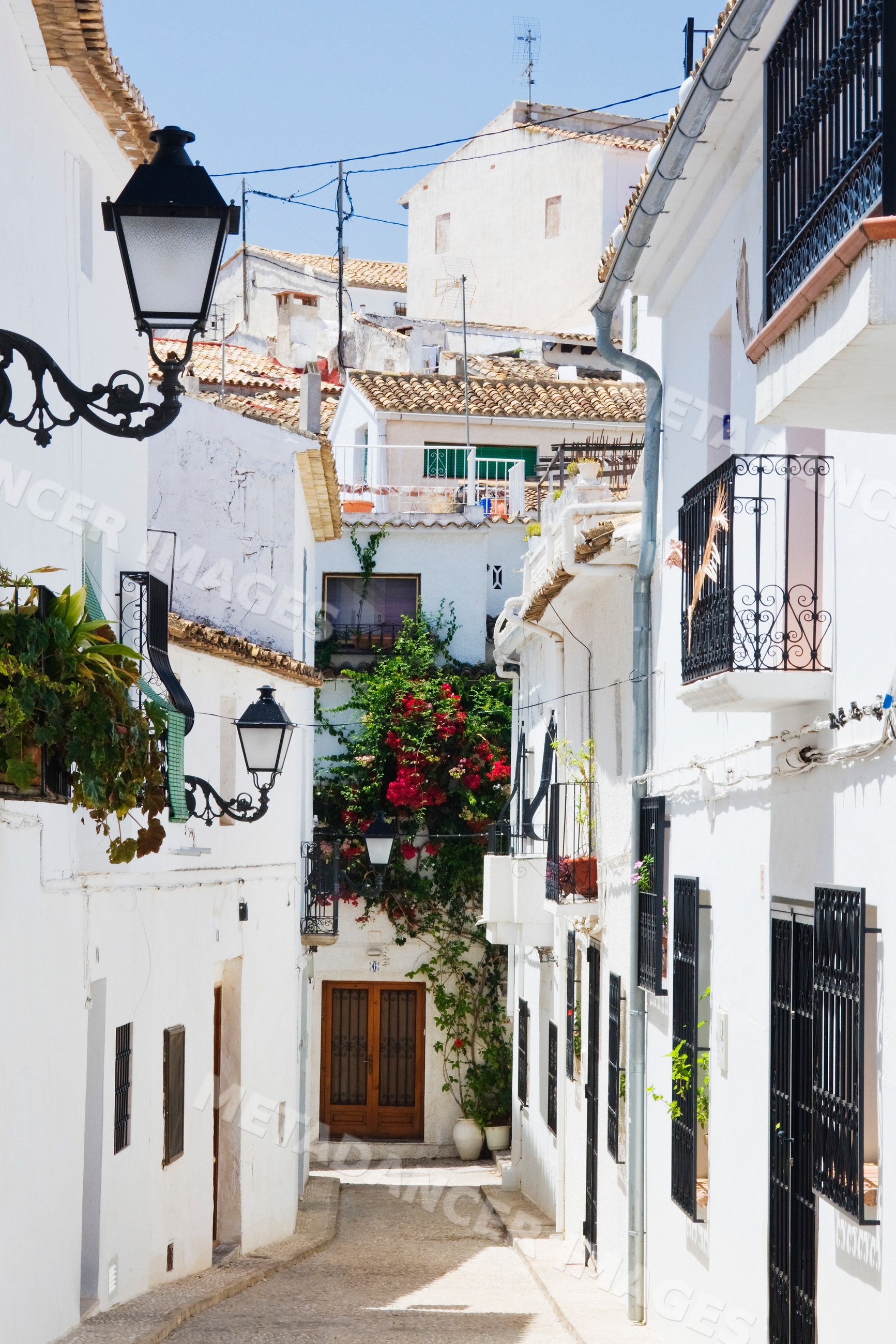 Narrow street with white buildings and flowers, valencia, Spain