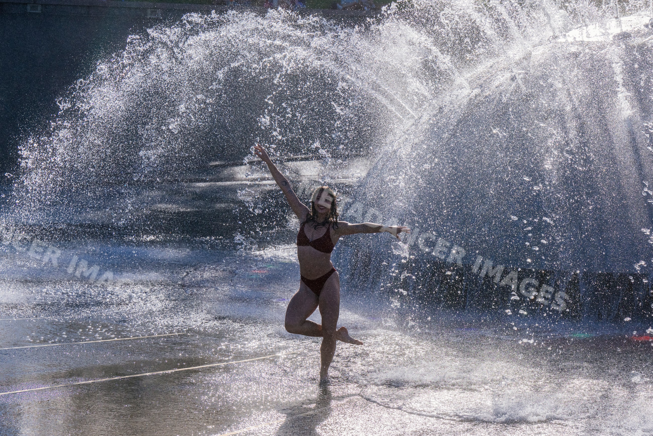 White woman dancing and playing in water fountain outdoors