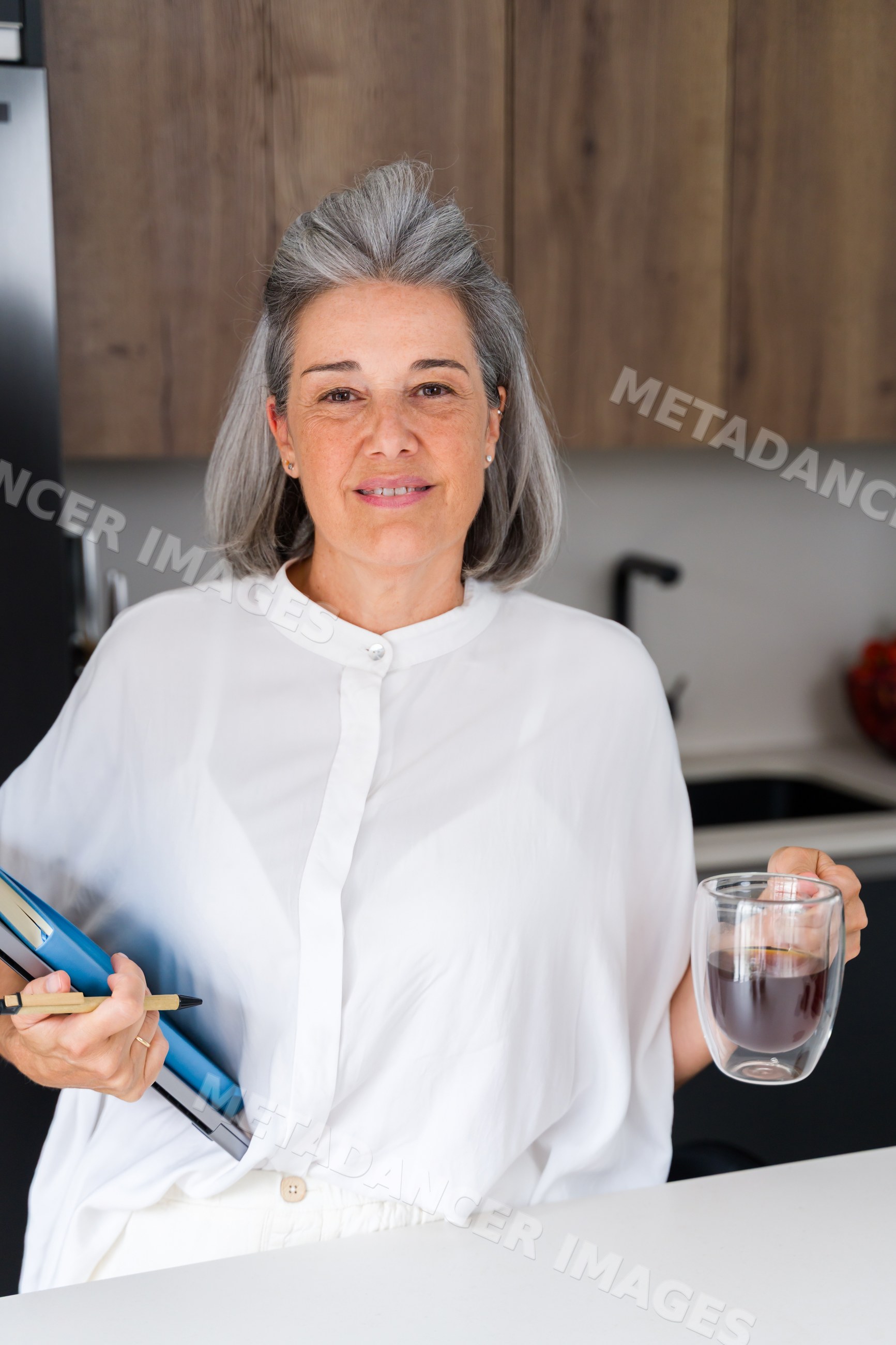 White Woman holding coffee and notebooks in modern kitchen in Spain