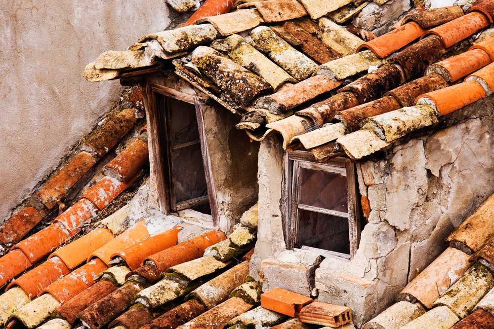 Close-up of weathered terracotta roof tiles and cracked plaster wall
