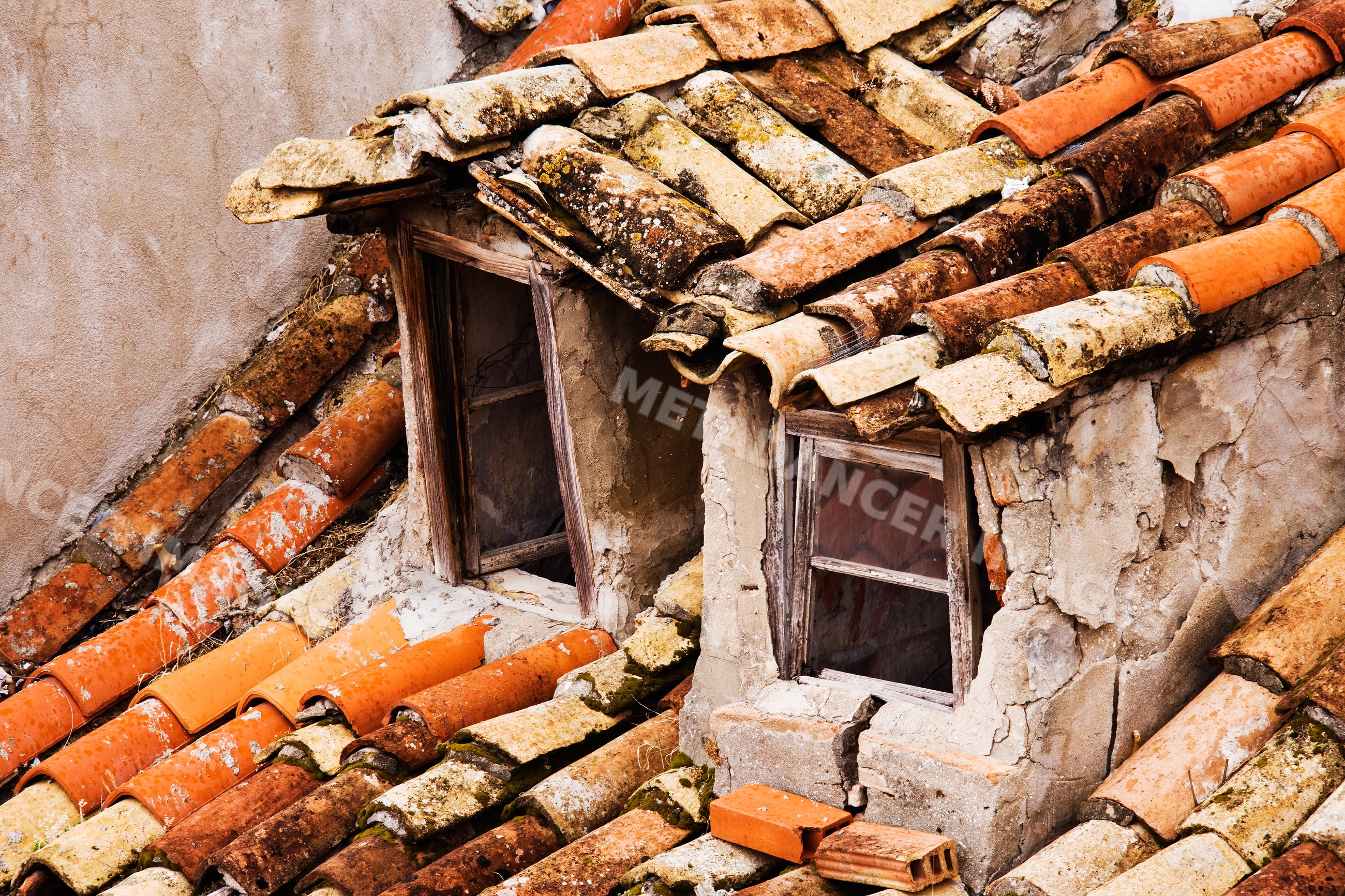 Close-up of weathered terracotta roof tiles and cracked plaster wall