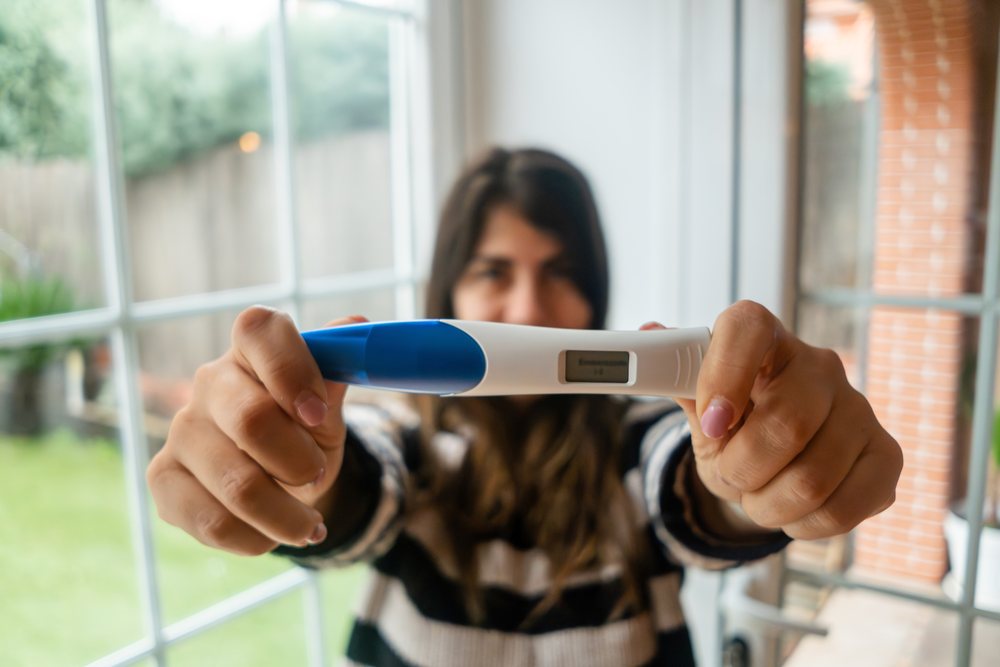 A white woman holds a digital pregnancy test
