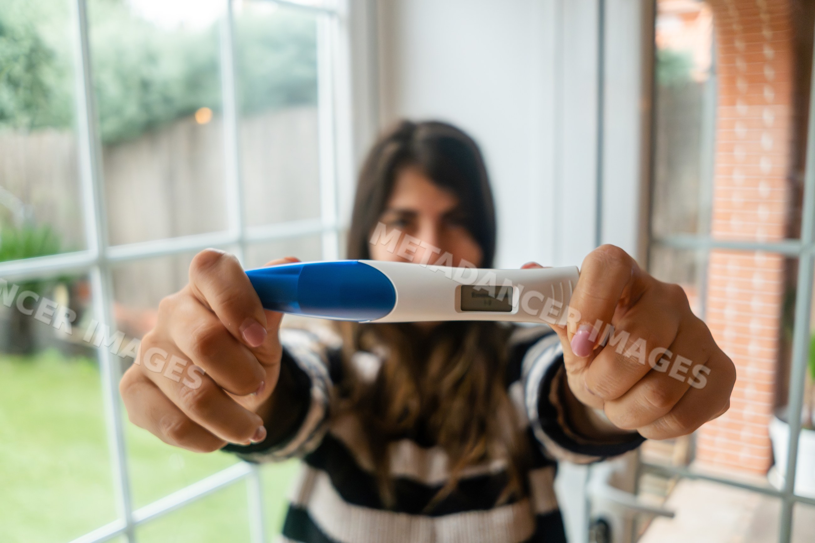 A white woman holds a digital pregnancy test