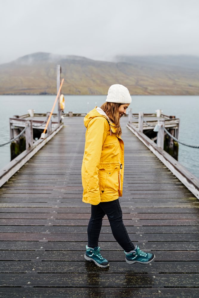 A white woman walks along a wooden pier over water