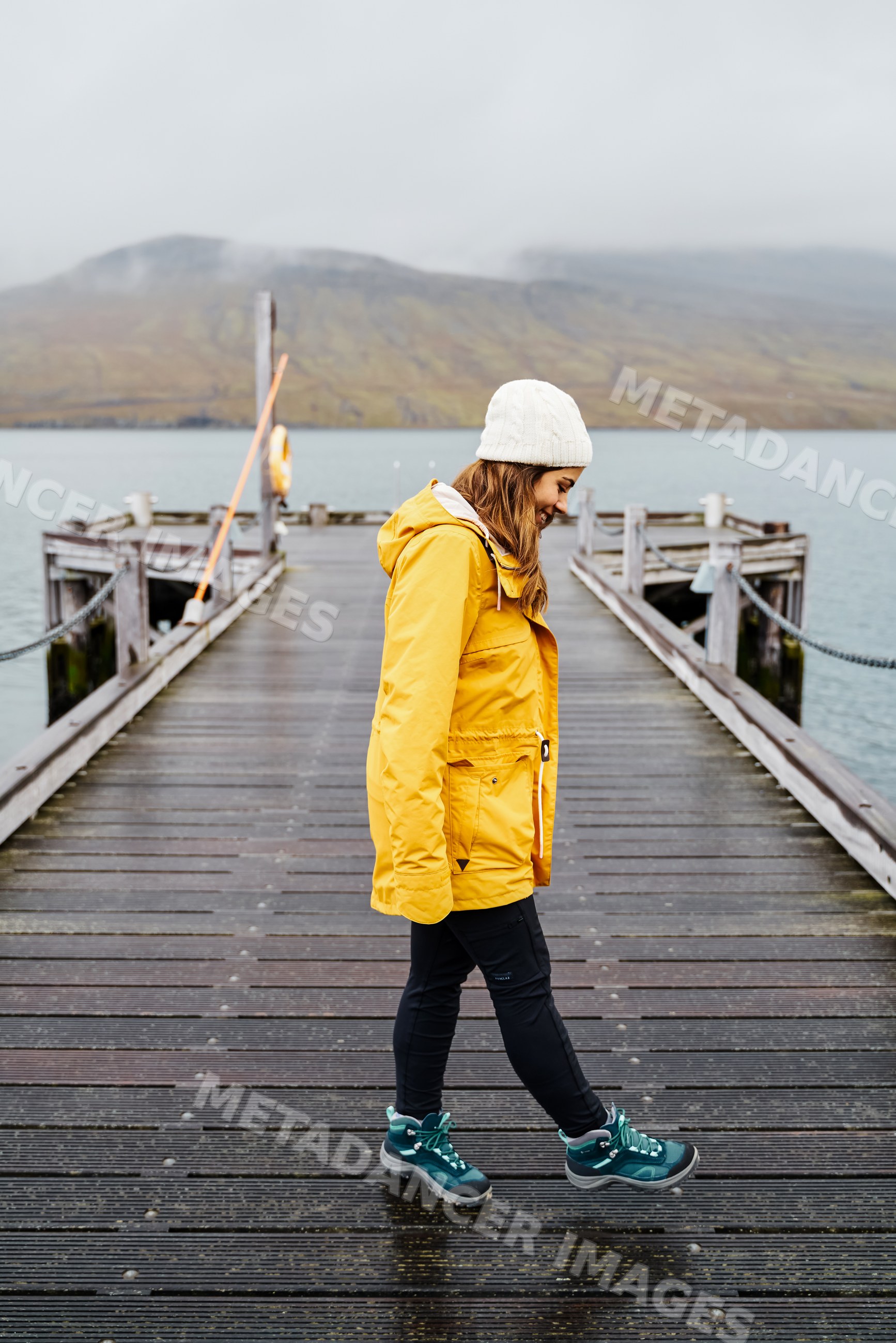 A white woman walks along a wooden pier over water