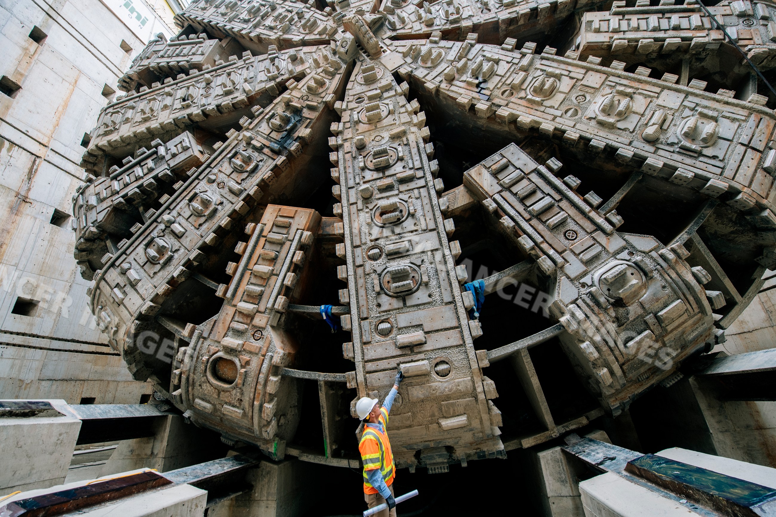 Construction white worker inspects tunnel boring machine drilling