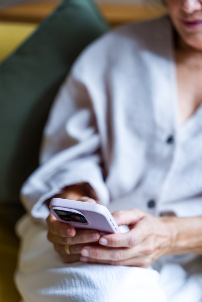 White woman sitting using smartphone in casual indoor environment