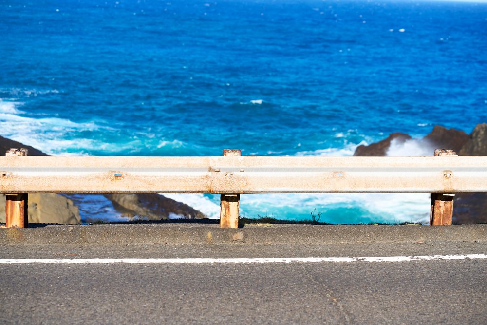 Coastal highway road with guardrail and ocean waves at shoreline