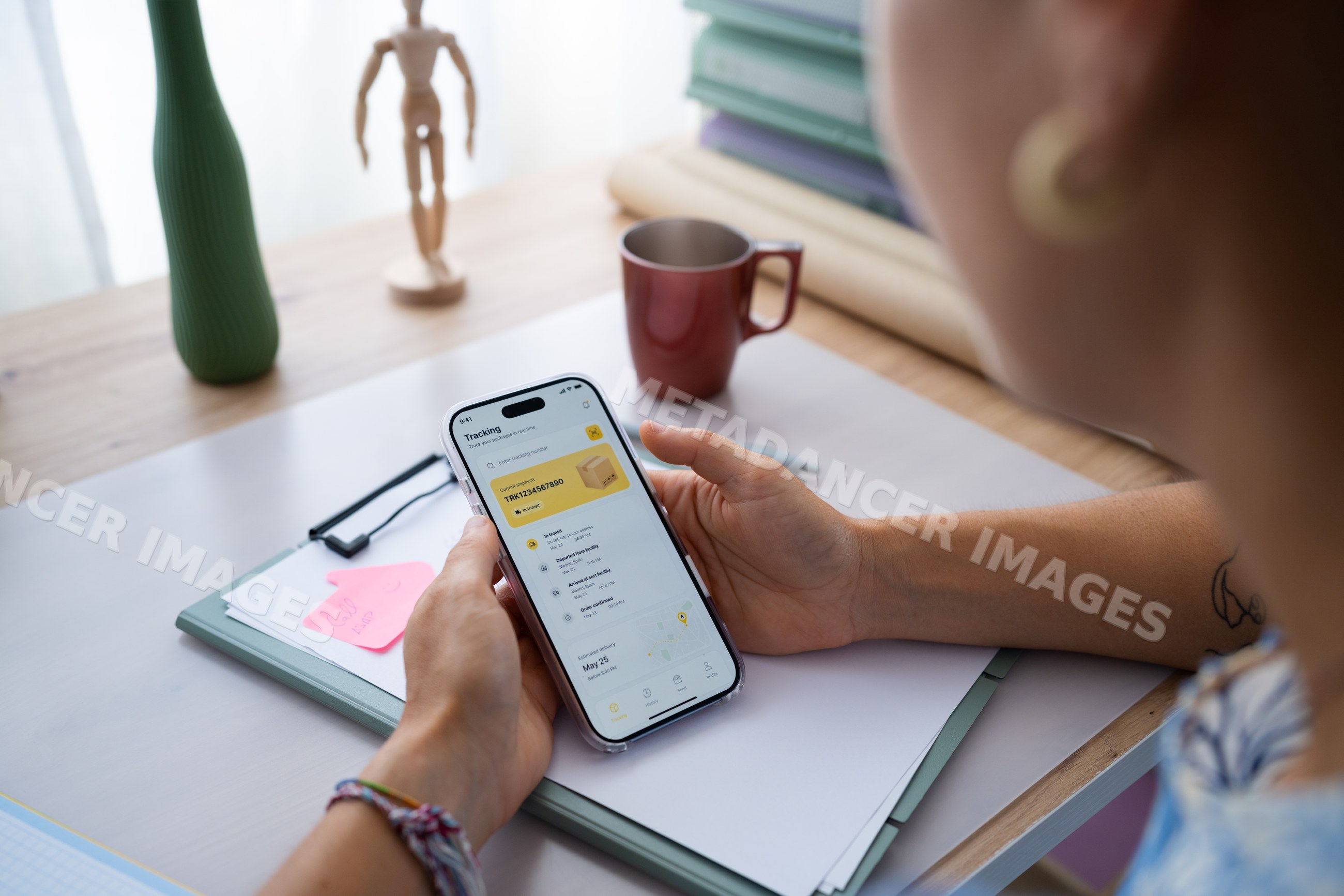 White person tracking package on phone at home office desk in a office