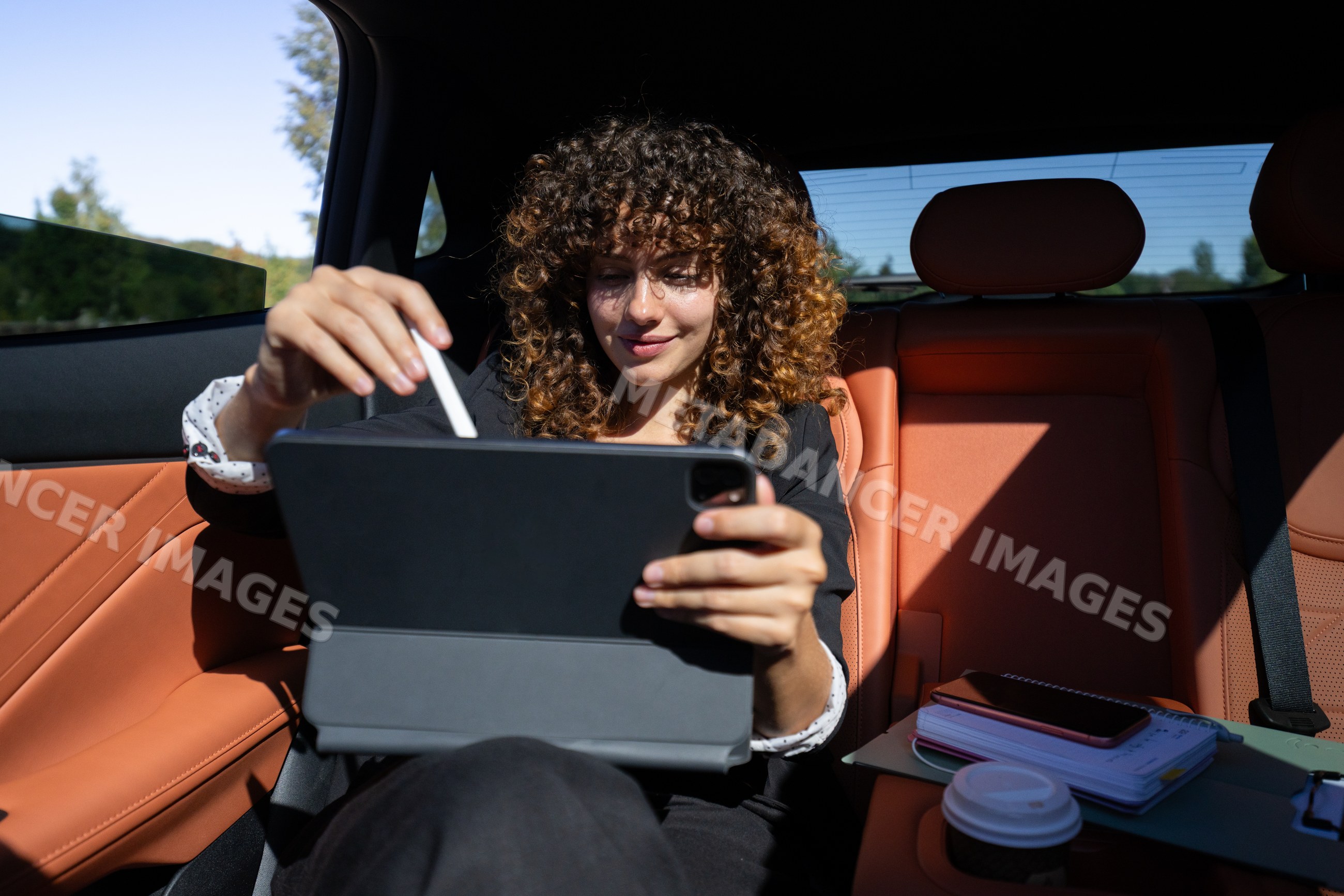 Businesswoman working remotely on tablet inside car