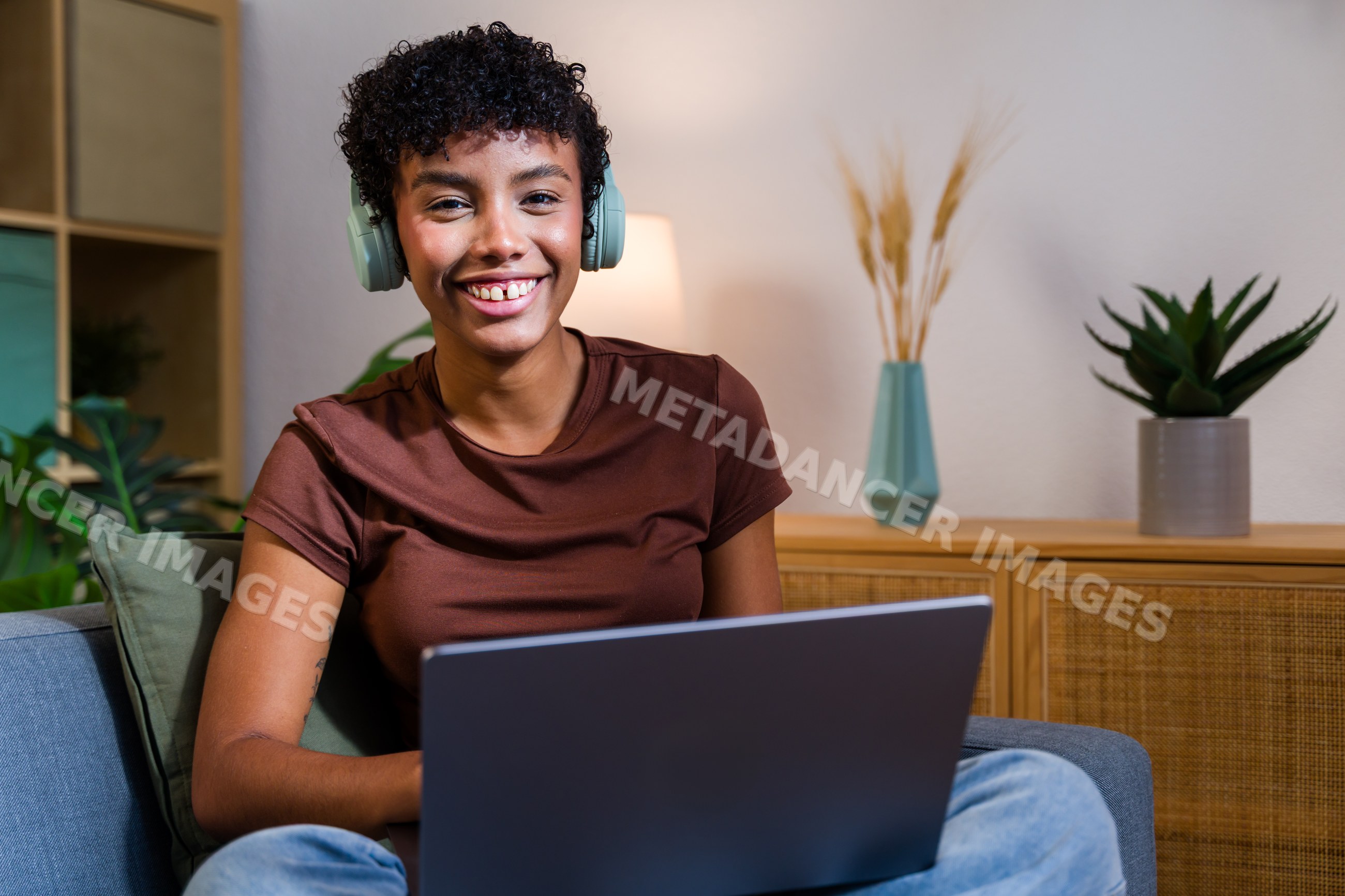 African American woman using laptop with headphones in living room