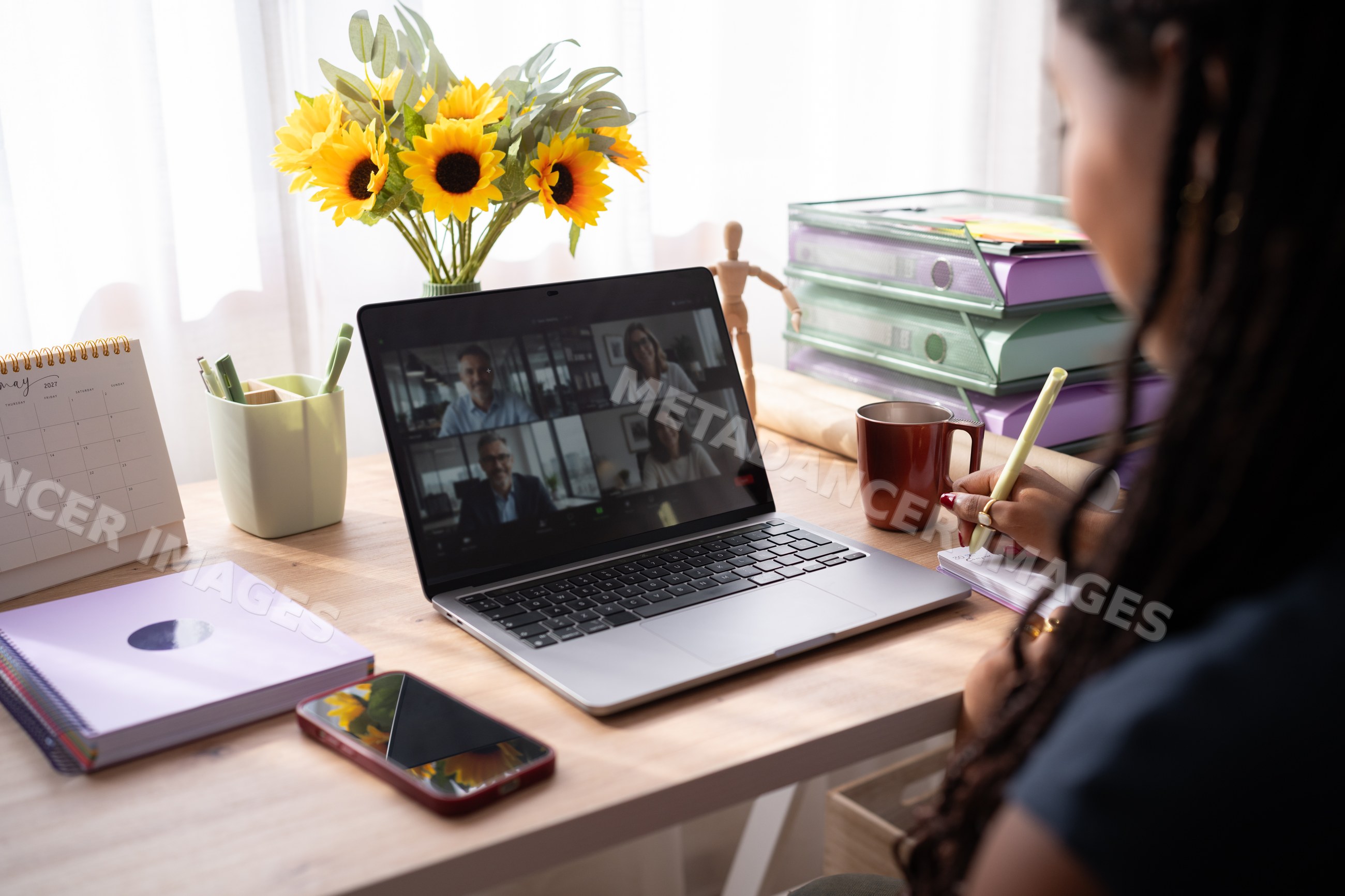 African American woman takes notes during a video call