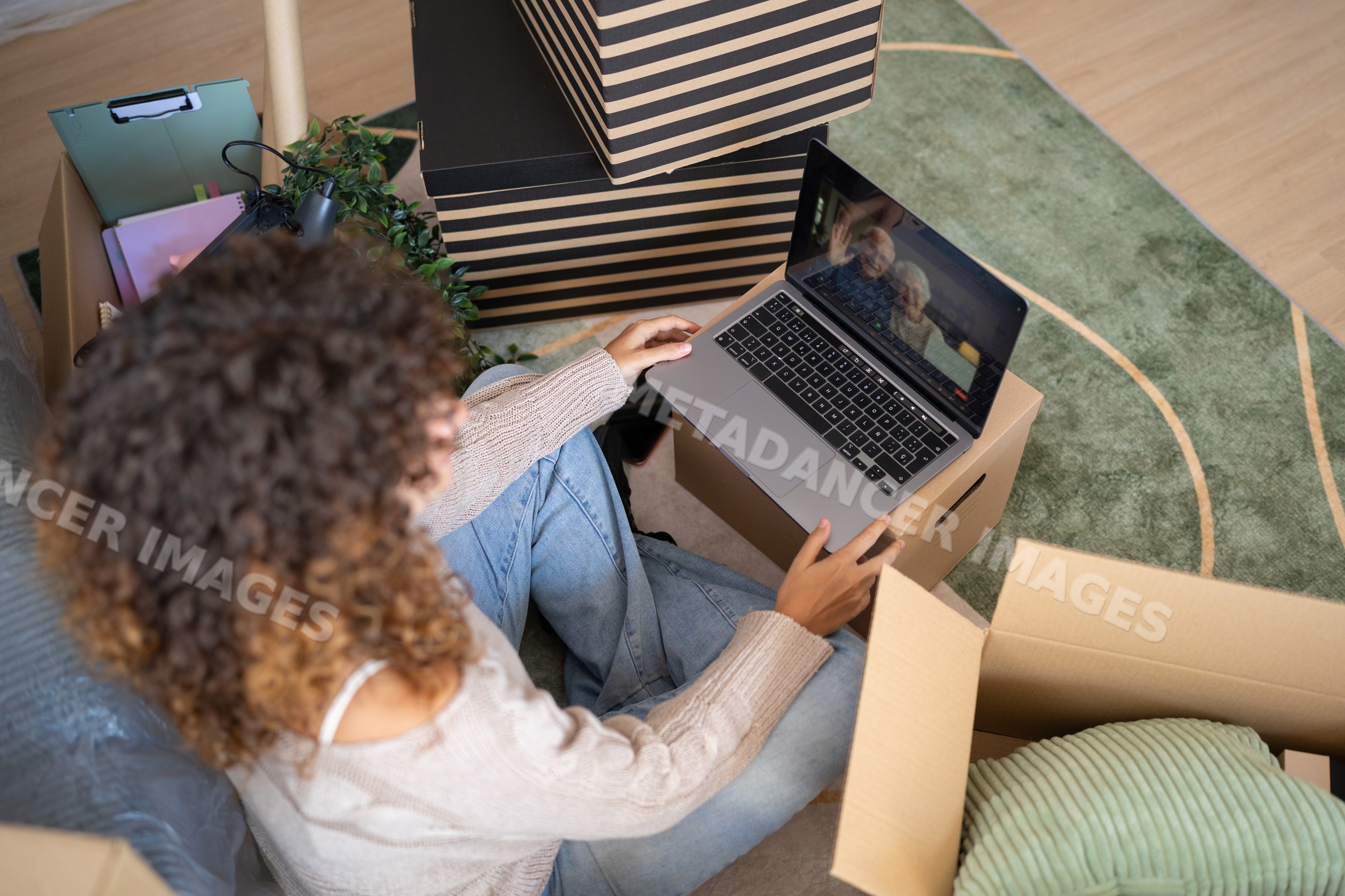 White woman using laptop for video chat while moving with packed boxes