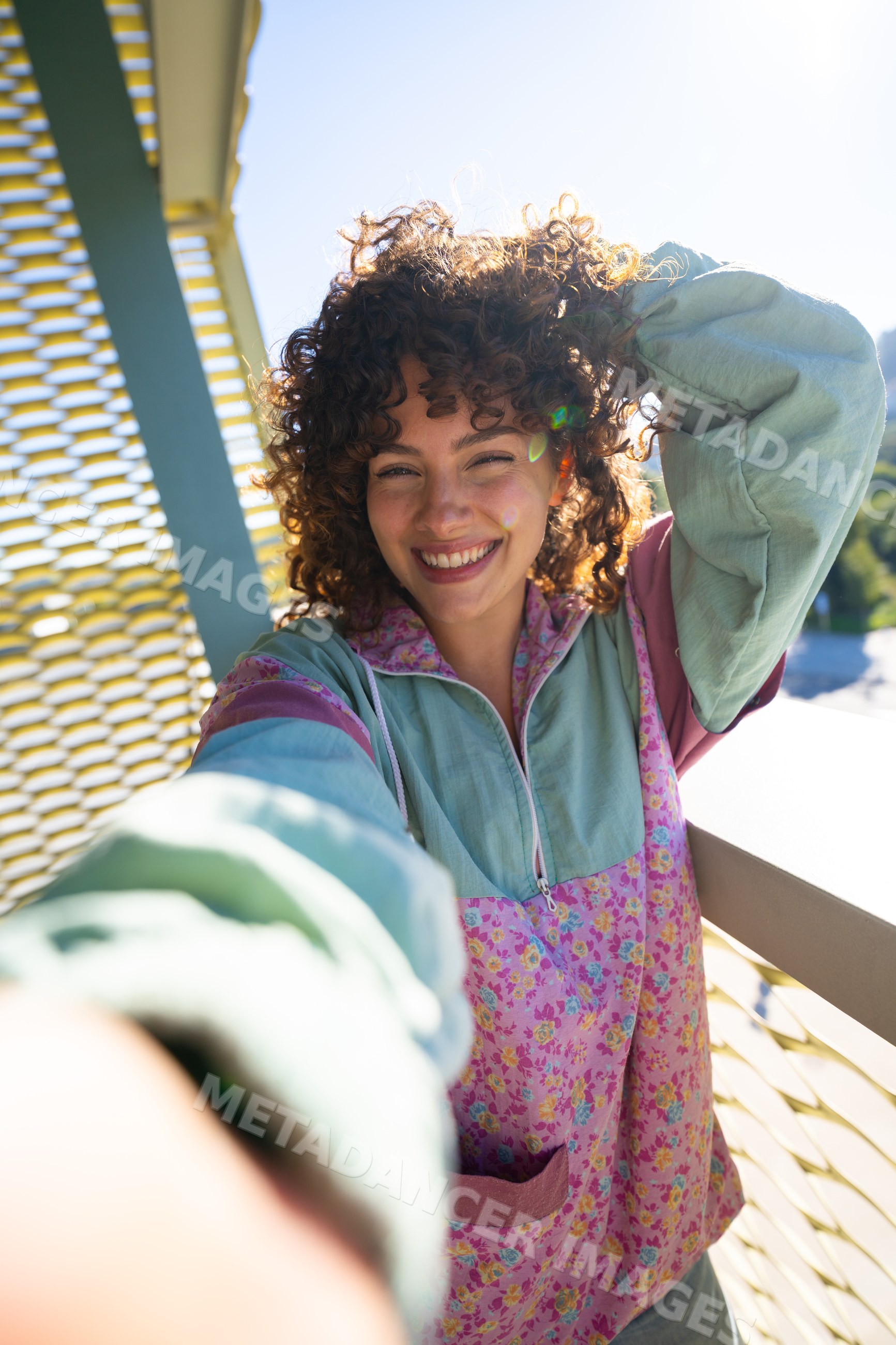 White woman smiling outdoors taking a selfie in sunlight