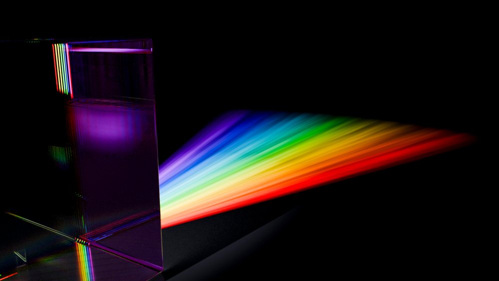 Glass prism refracting white light into rainbow spectrum