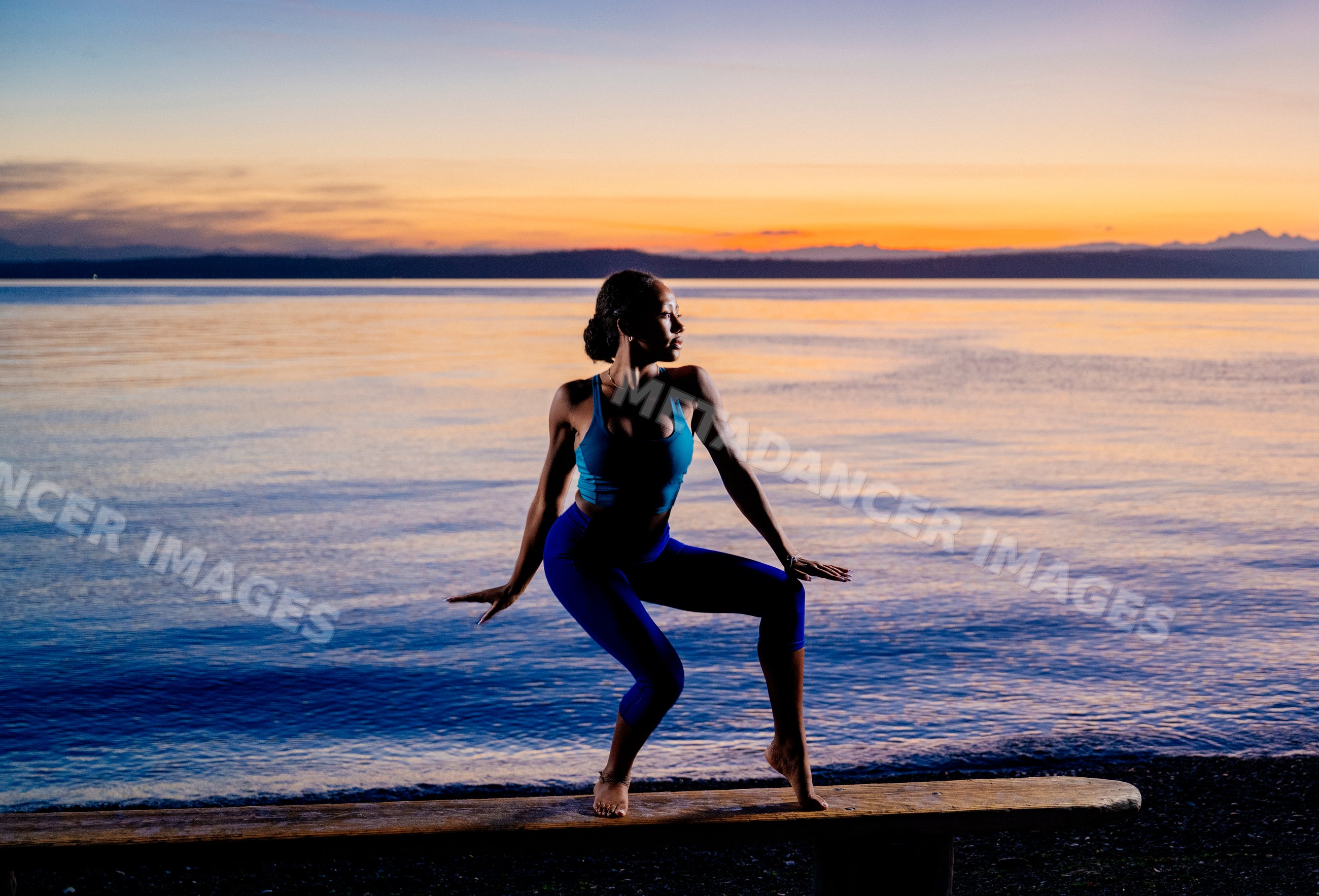 Hispanic woman practicing yoga stretching pose on bench by the seaside