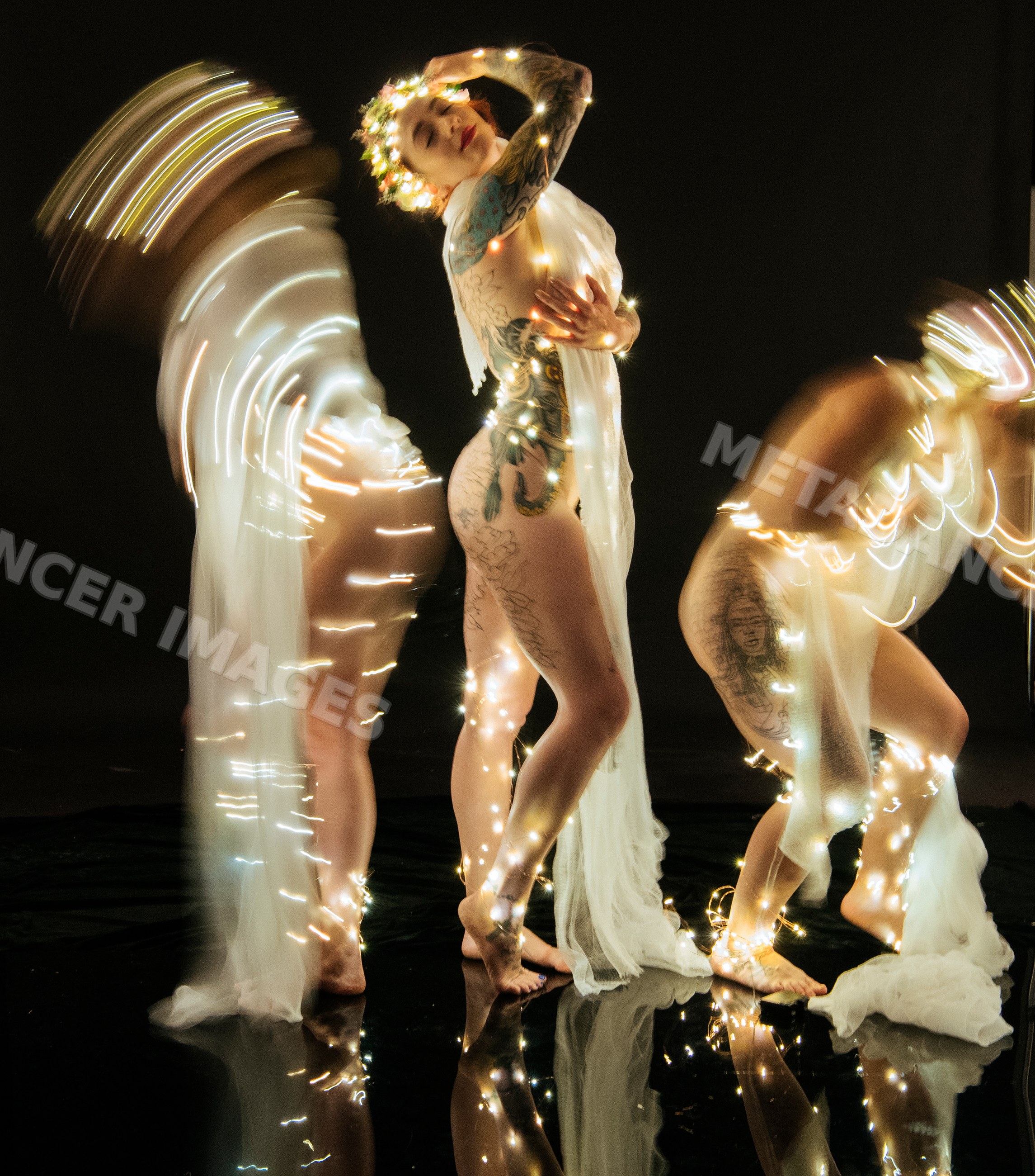 Three muses with tattoos posing artistically in fairy lights