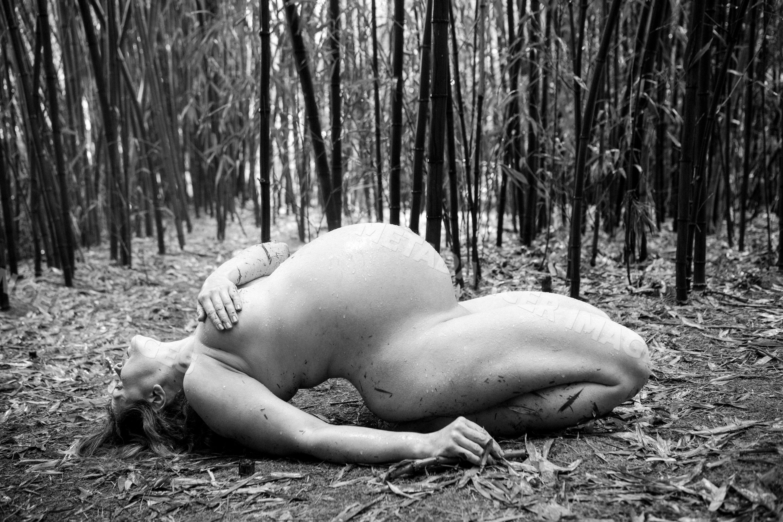 Pregnant white woman lying nude in bamboo forest