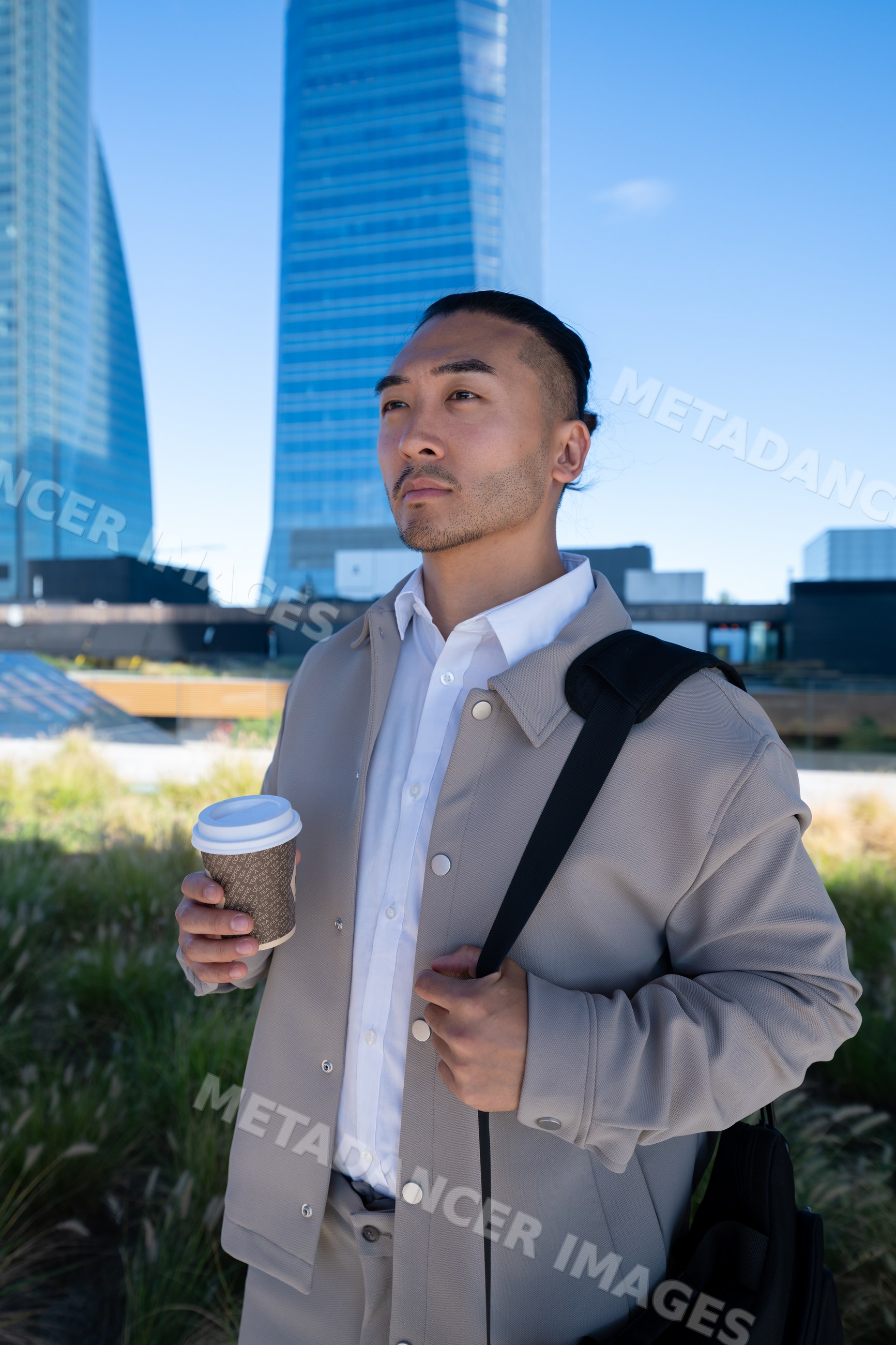 Man holding coffee outdoors near modern skyscrapers in Madrid, Spain