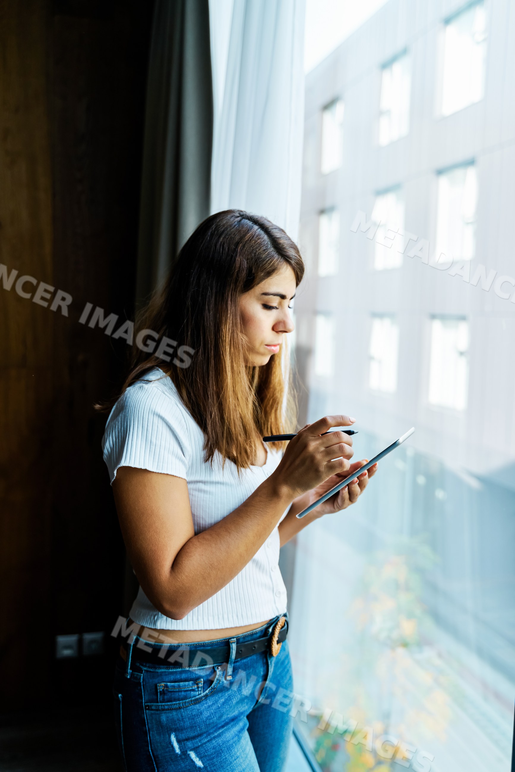 A woman uses a digital pen on a tablet indoors