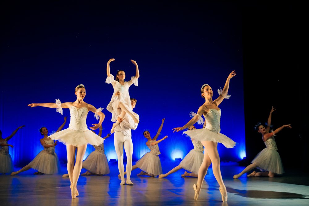 Ballet dancers perform a classical lift and dance routine on stage