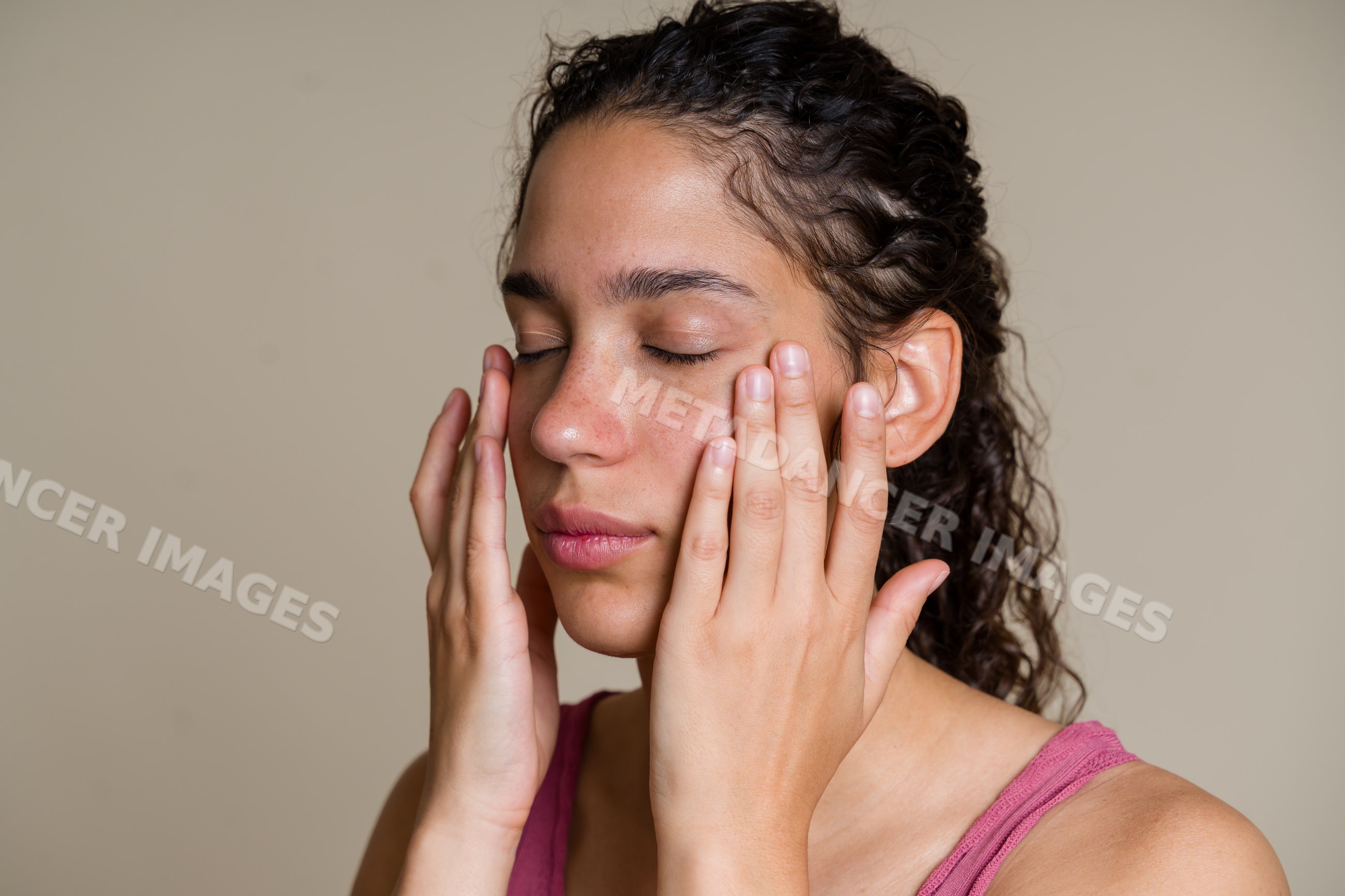 Hispanic woman applying moisturizer to her face in skincare routine