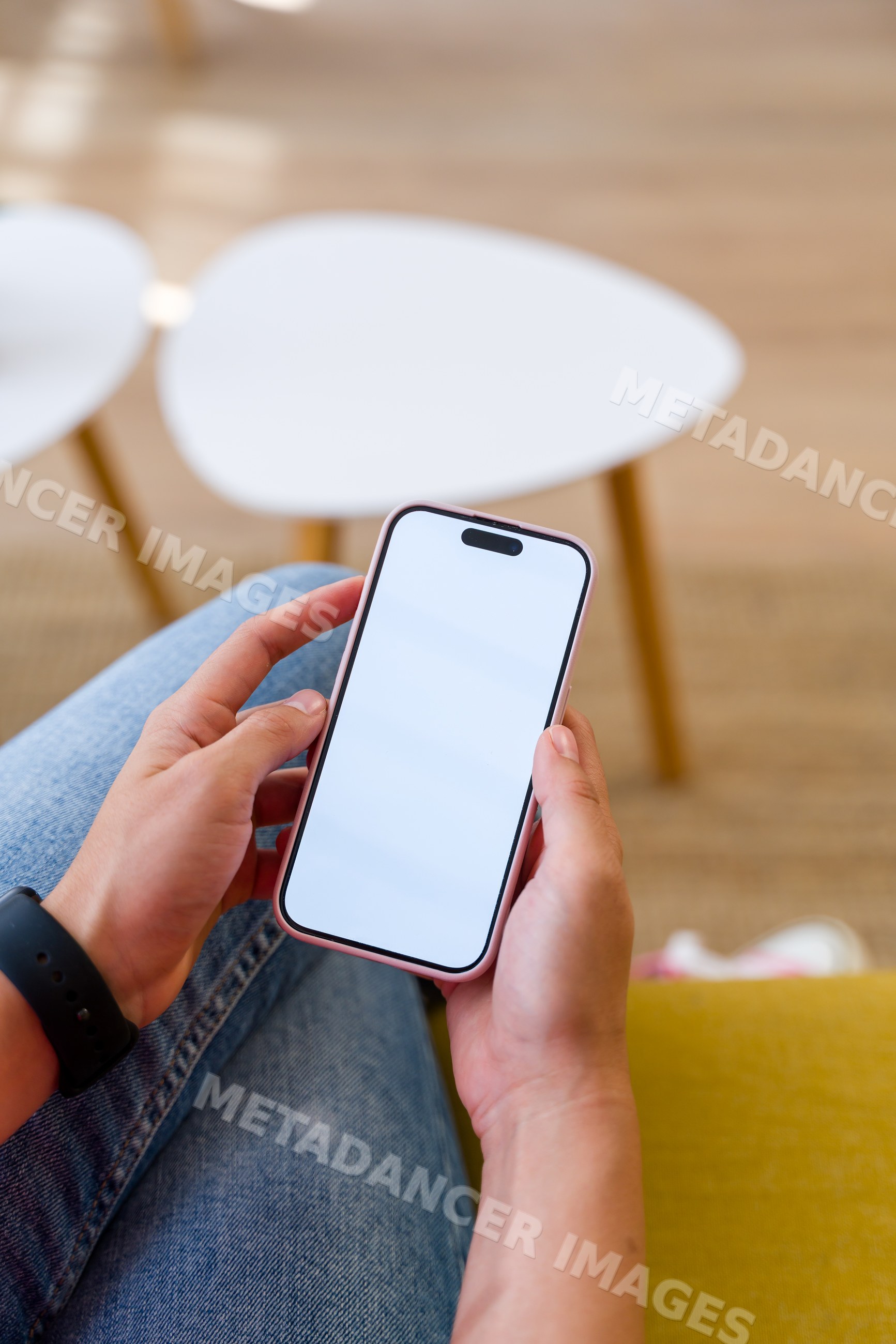 A Hispanic person holding a smartphone with a blank screen indoors